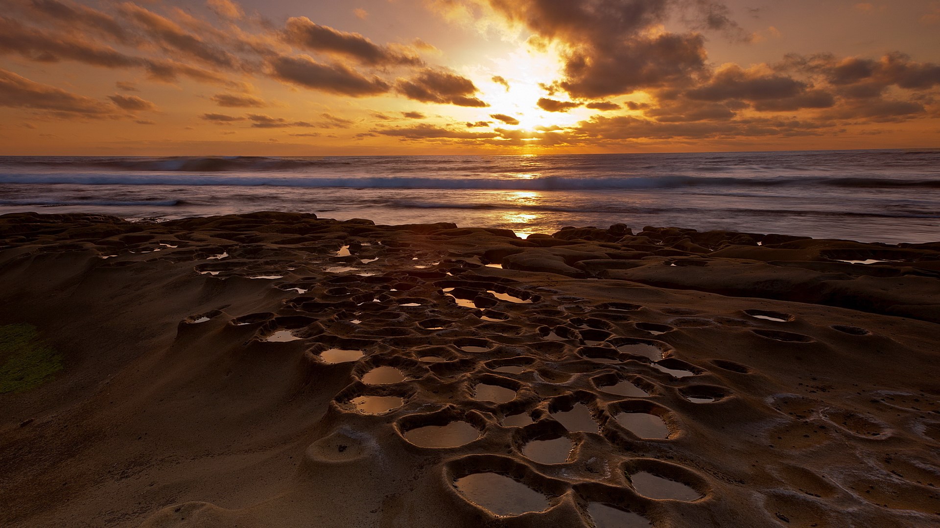 Sunset over the ocean with tide pools on rocky shore HD Wallpaper