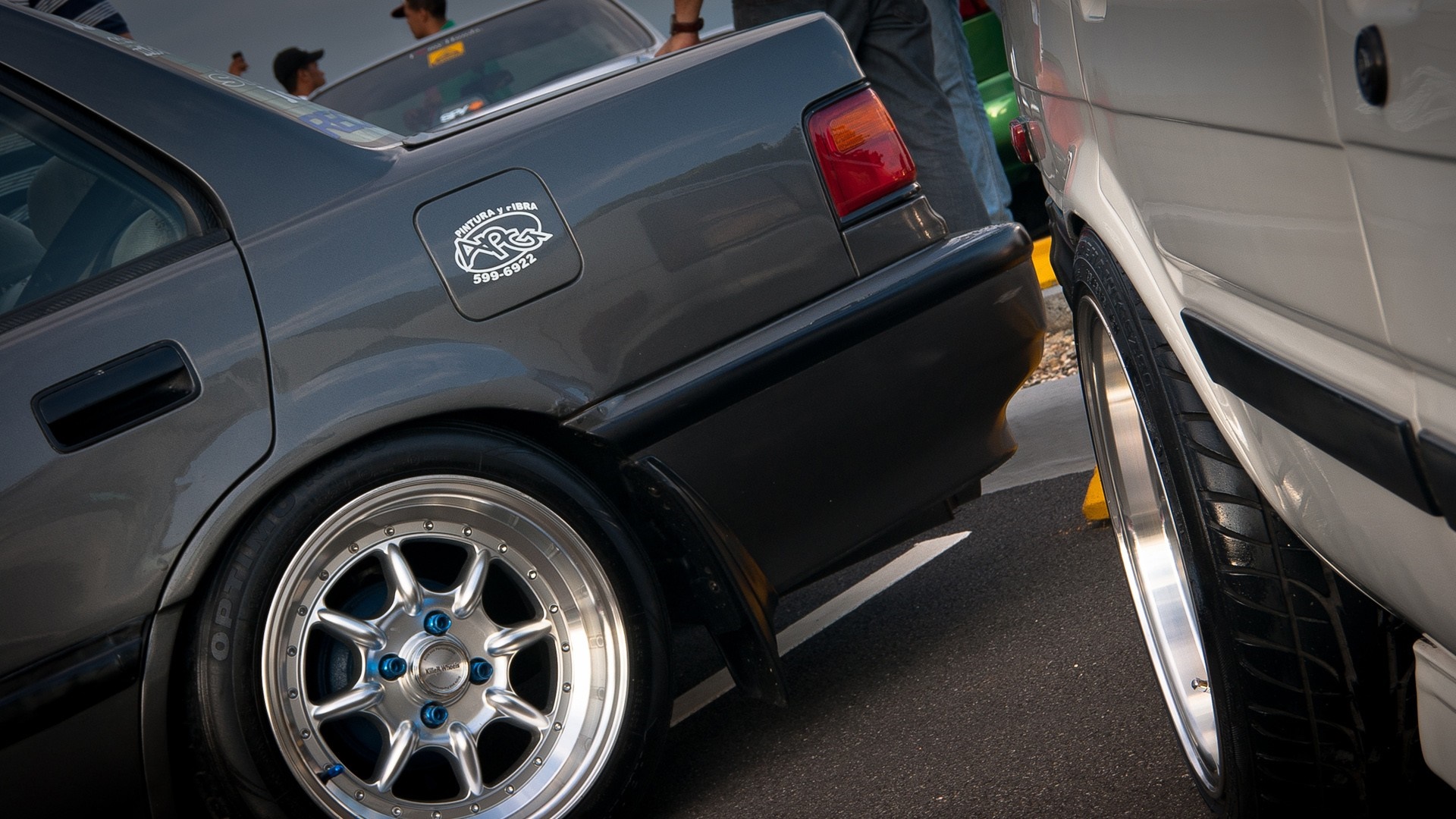 Two cars with custom rims parked side-by-side HD Wallpaper