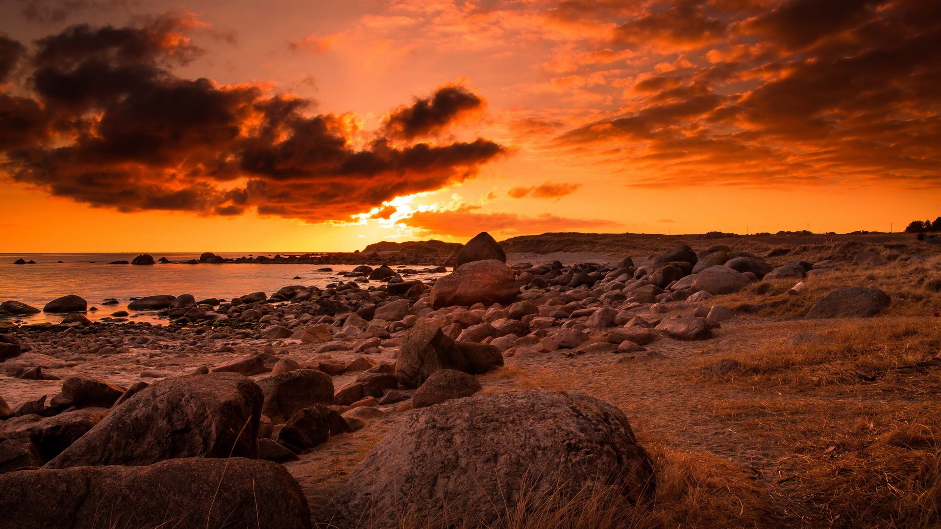 Rocky beach at sunset with orange sky HD Wallpaper