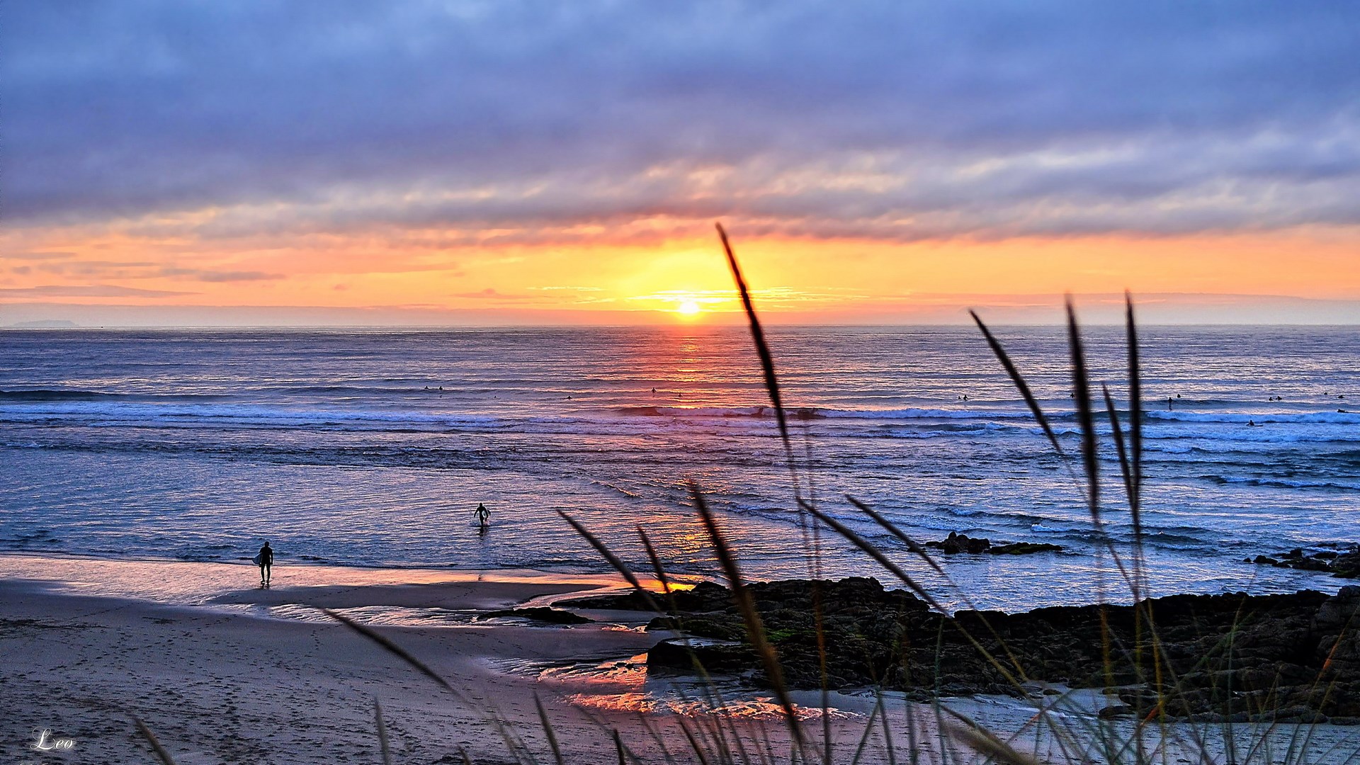 Surfers at sunset on a beach HD Wallpaper