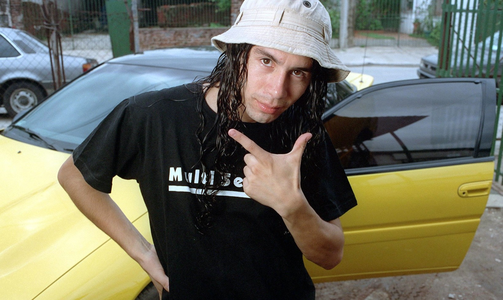 Man with long hair and bucket hat pointing HD Wallpaper