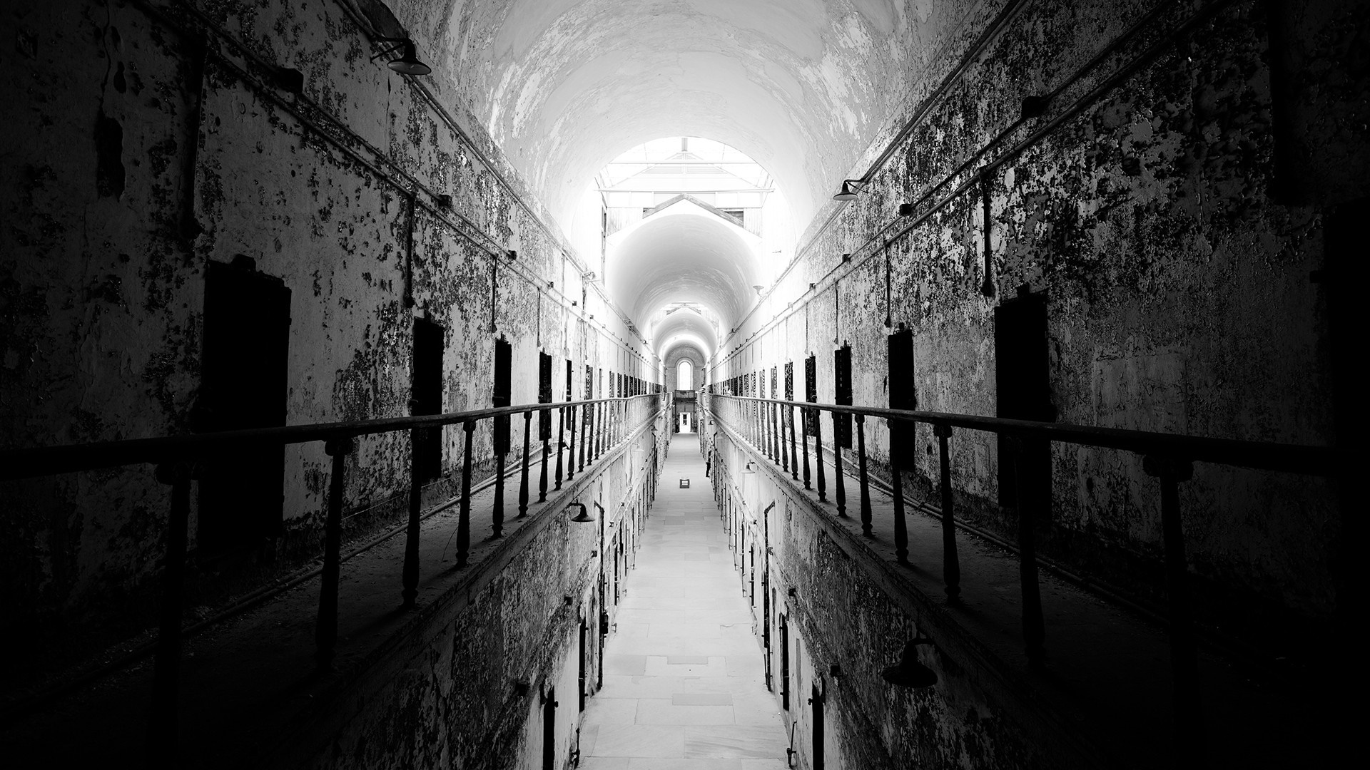 Abandoned prison hallway with cells and sunlight HD Wallpaper