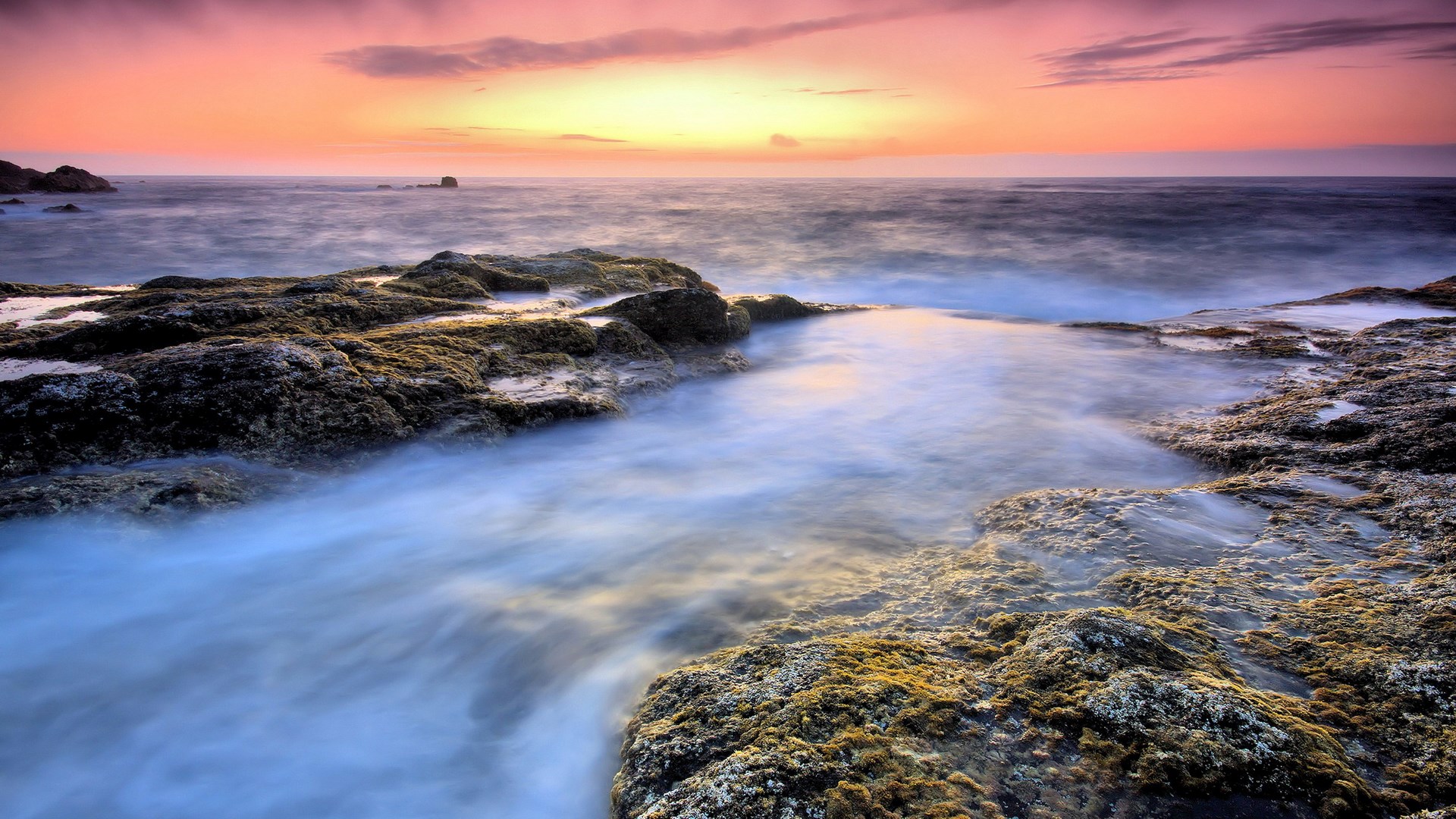 Ocean waves crashing on rocky shore at sunset HD Wallpaper
