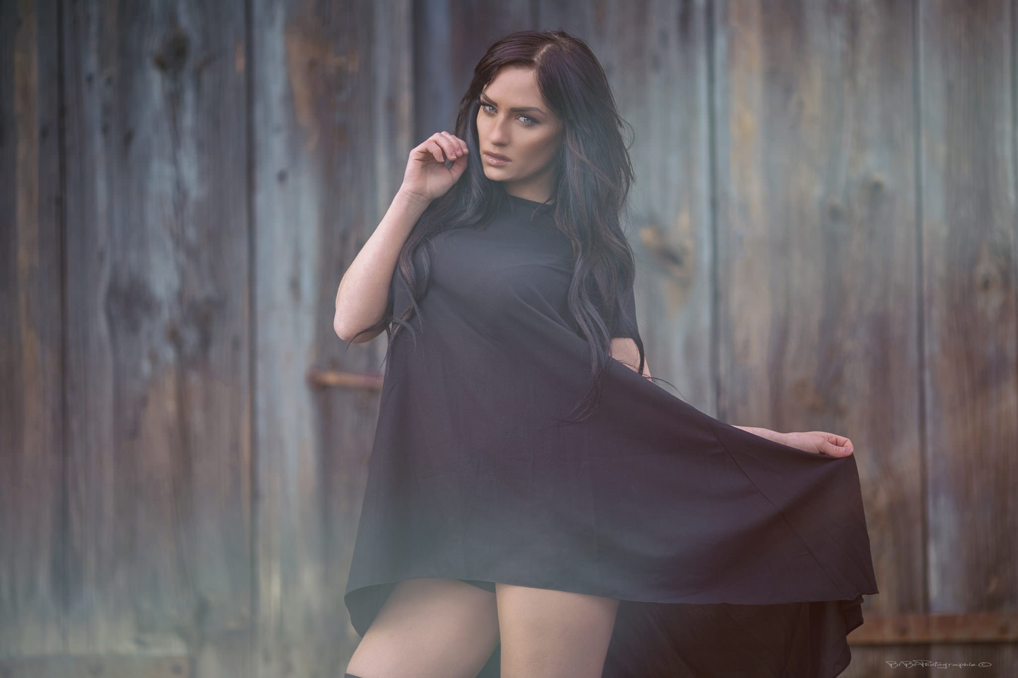Woman in black dress posing against wooden background HD Wallpaper