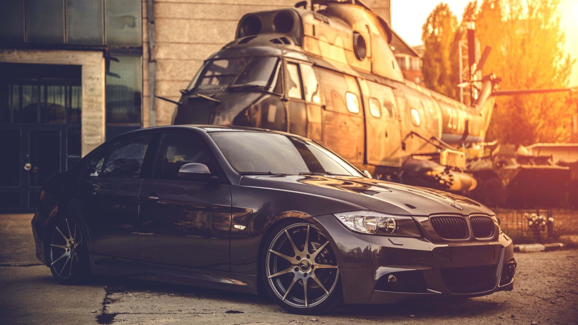 Dark BMW sedan parked in front of a helicopter HD Wallpaper