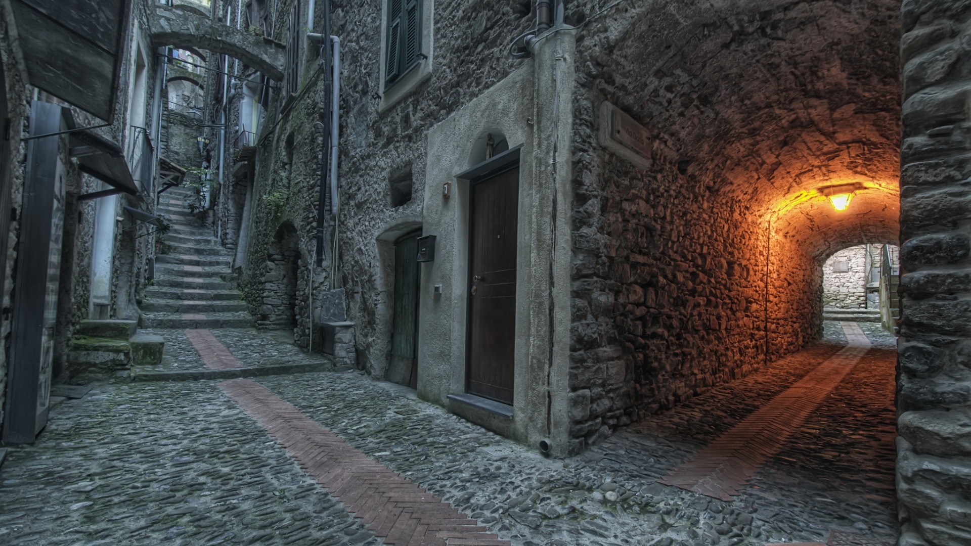 Stone alley with stairs and an illuminated archway HD Wallpaper