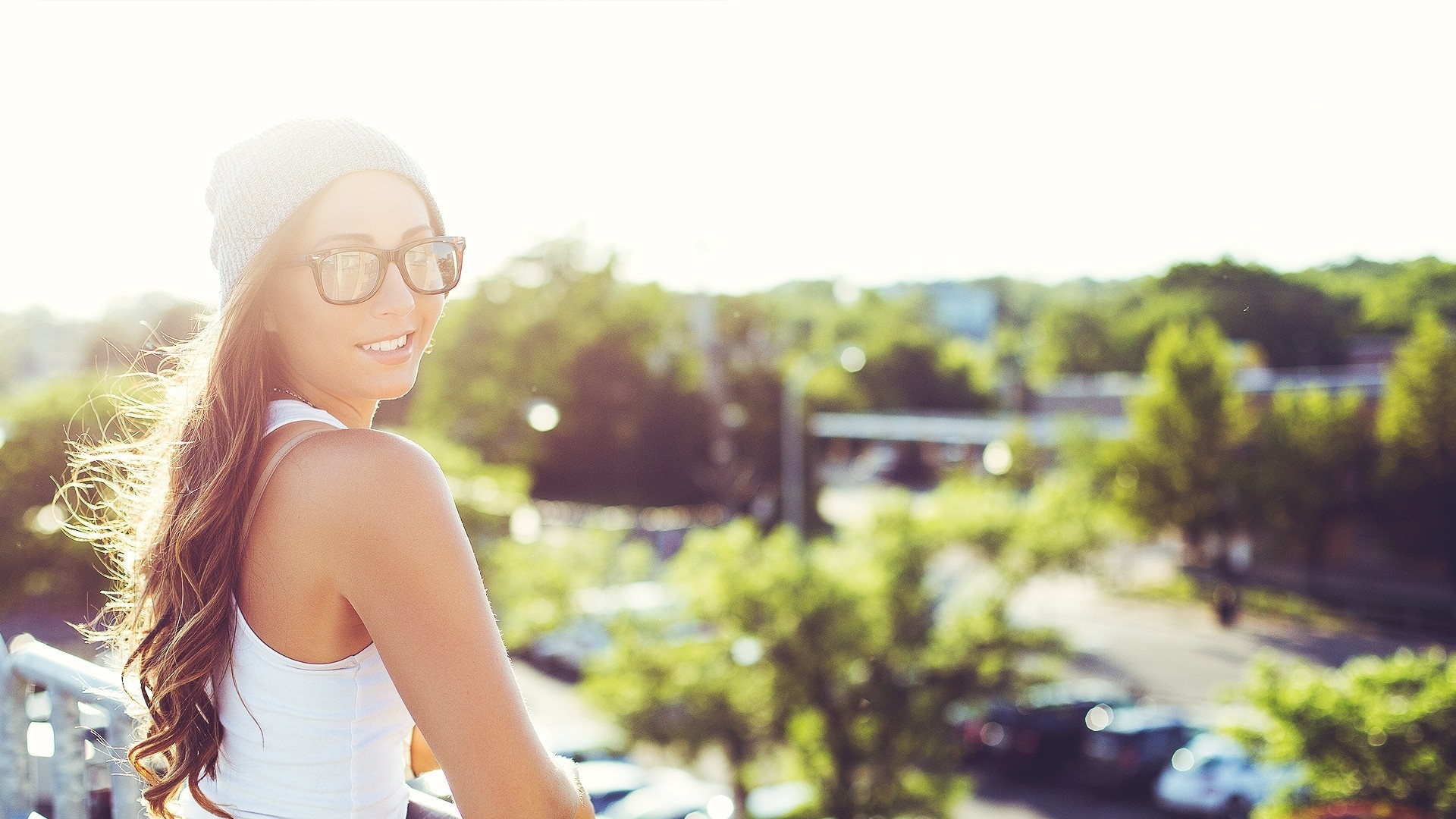 Woman wearing glasses and beanie with sun rays HD Wallpaper