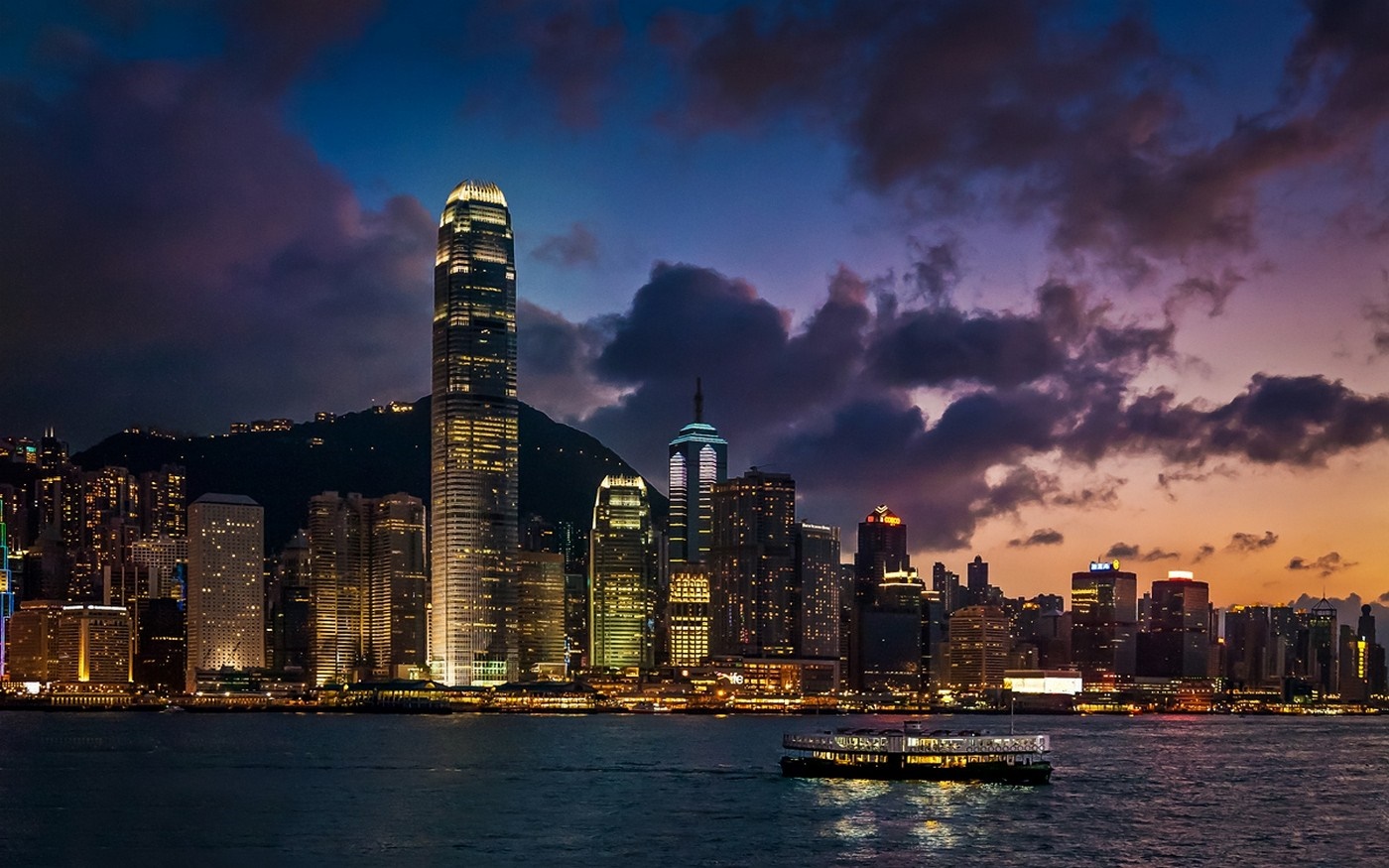 Hong Kong skyline at dusk with a ferry on the water HD Wallpaper