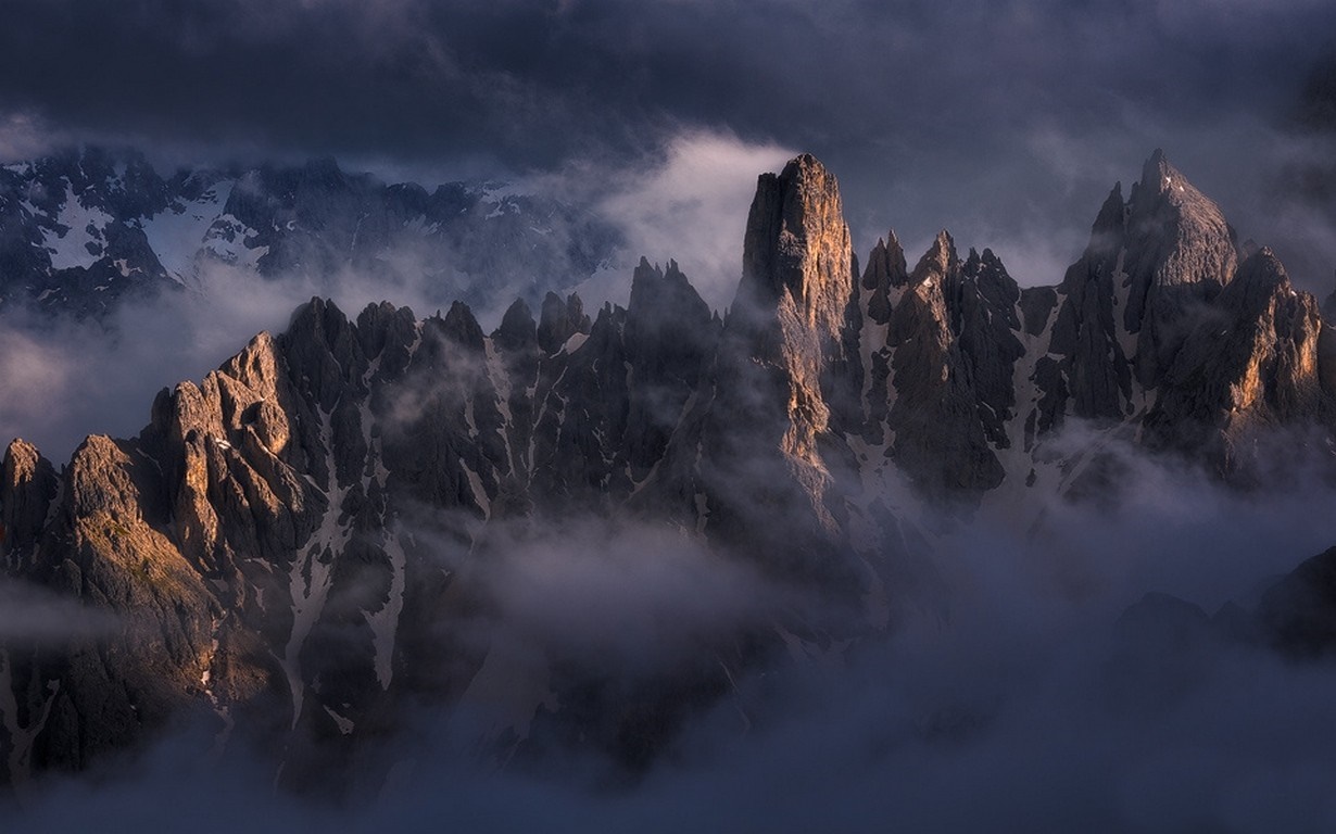 Jagged mountain peaks emerge from mist at sunrise HD Wallpaper