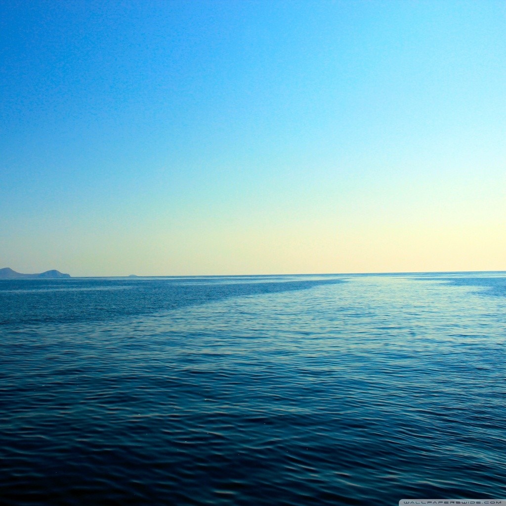 Ocean horizon with distant landmass under a clear sky HD Wallpaper