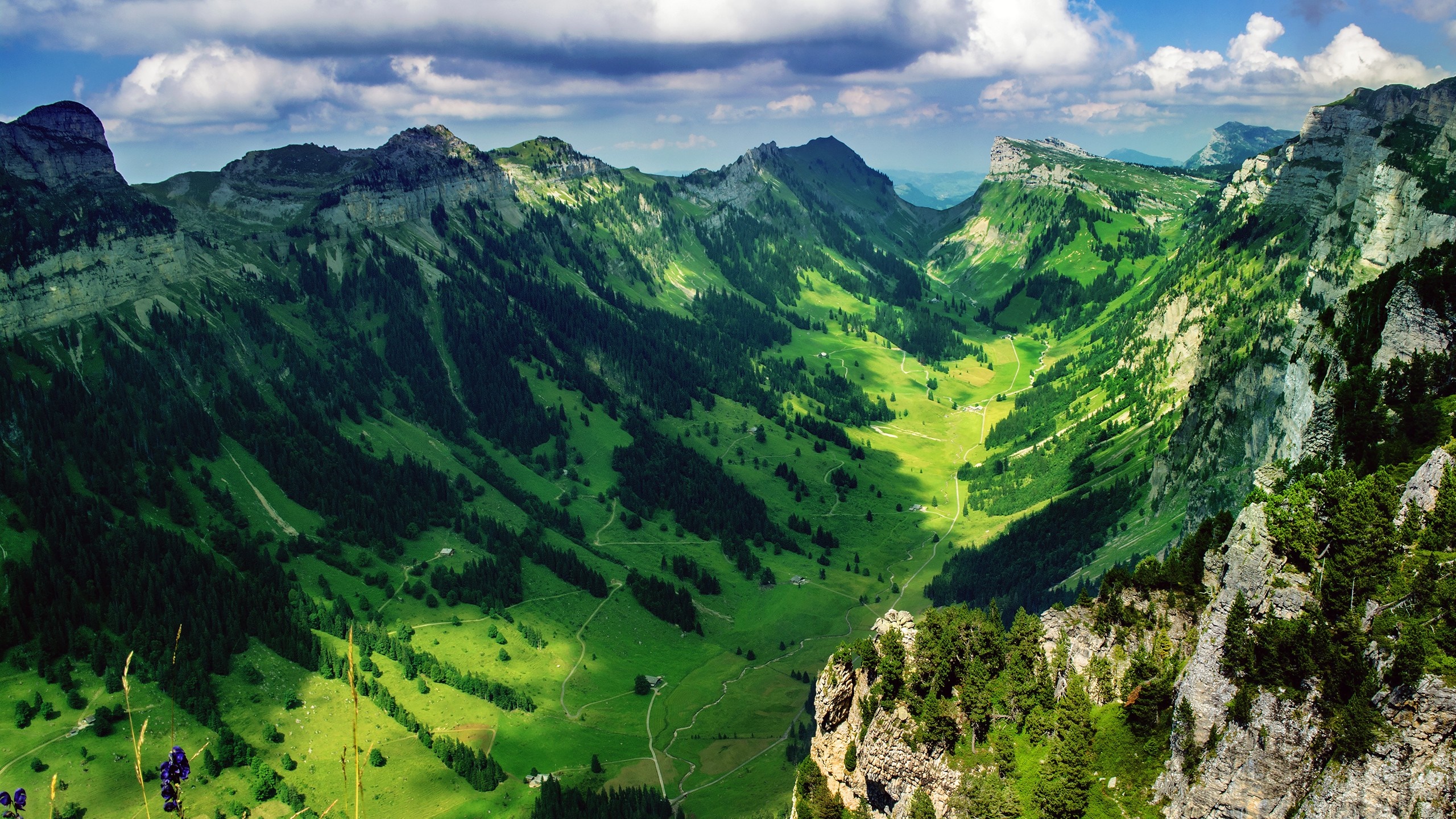 Green valley between mountains under a cloudy sky HD Wallpaper