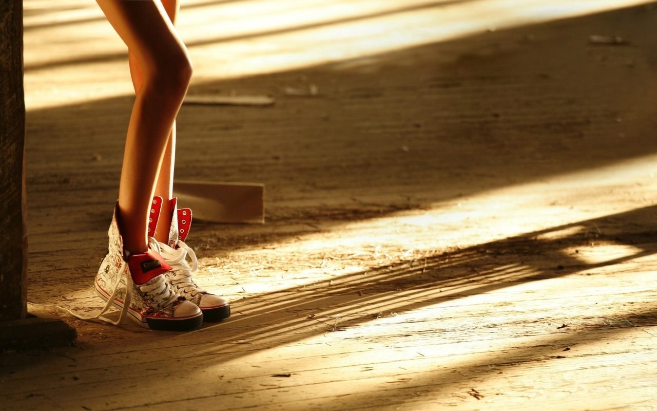 Legs wearing patterned high-top sneakers on a wooden floor HD Wallpaper