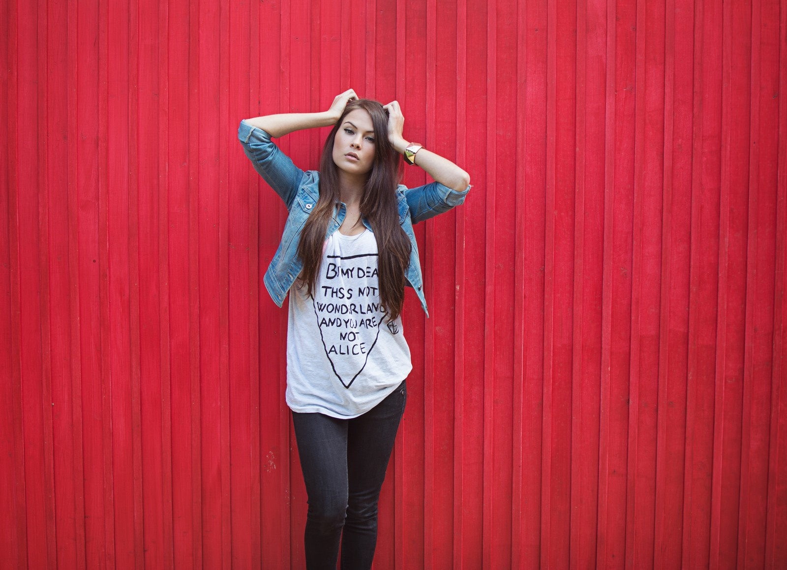 Woman in denim jacket and graphic t-shirt against red wall HD Wallpaper