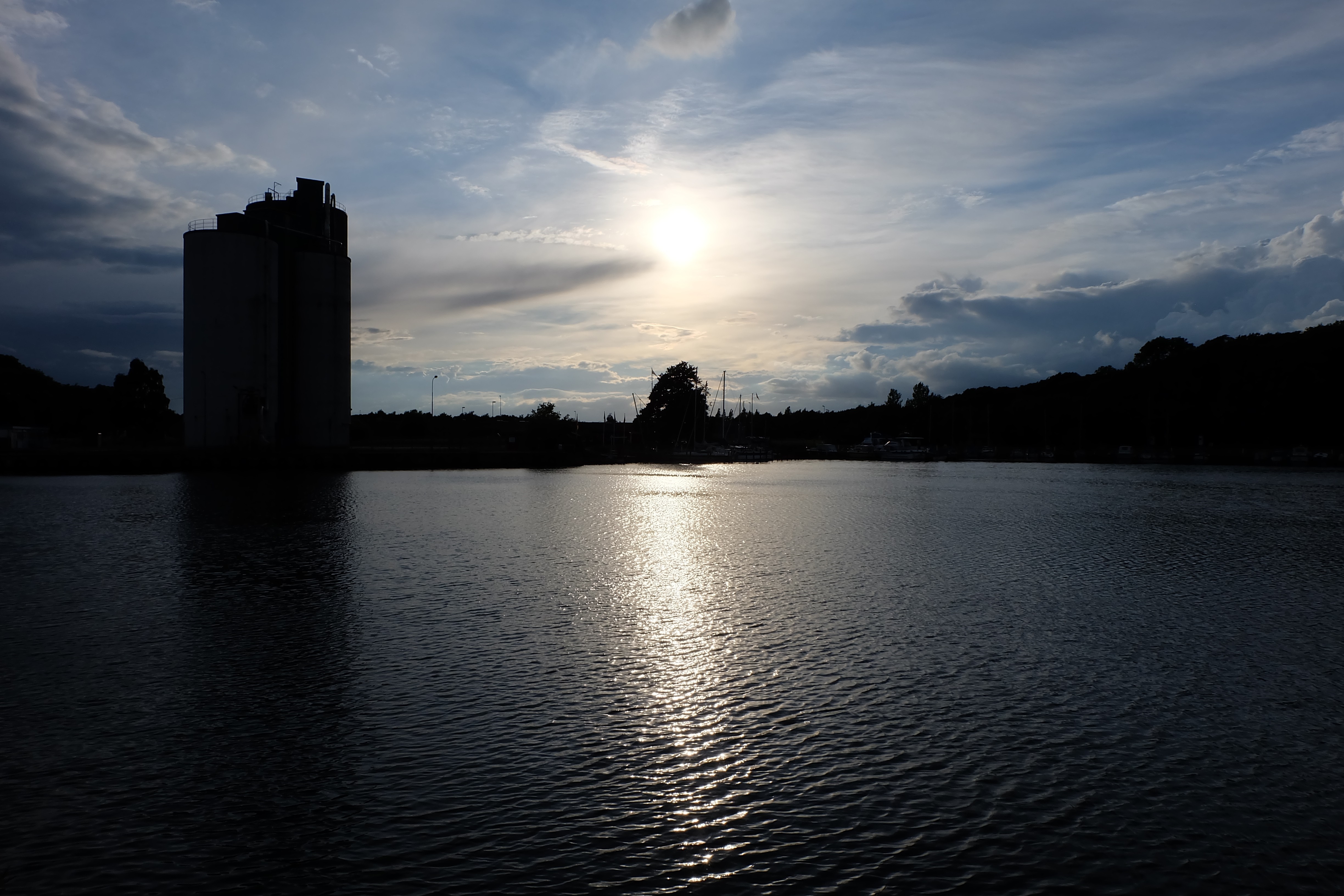 Silhouetted grain elevator by the water at sunset HD Wallpaper