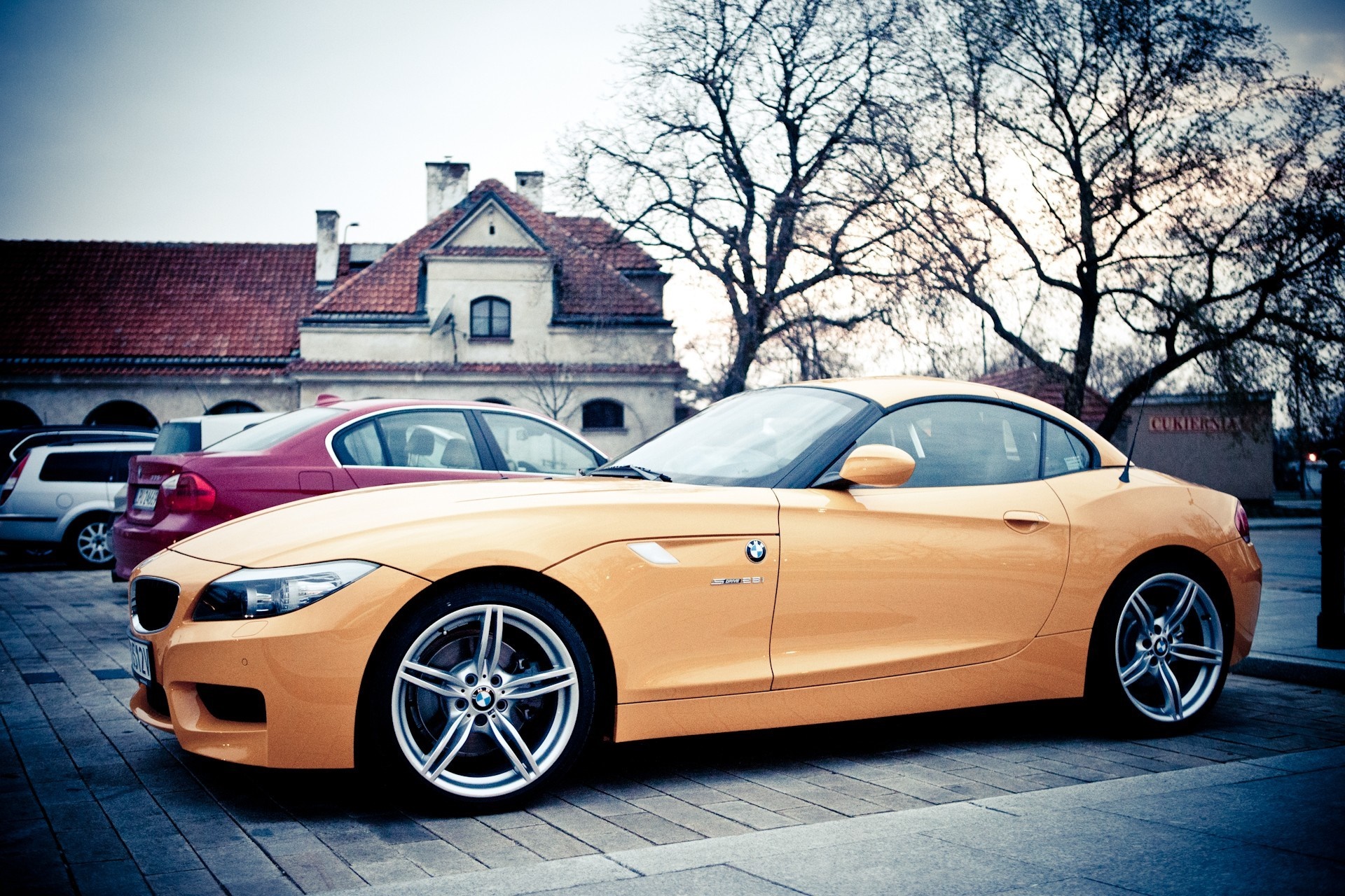 Orange BMW Z4 parked in front of a building HD Wallpaper
