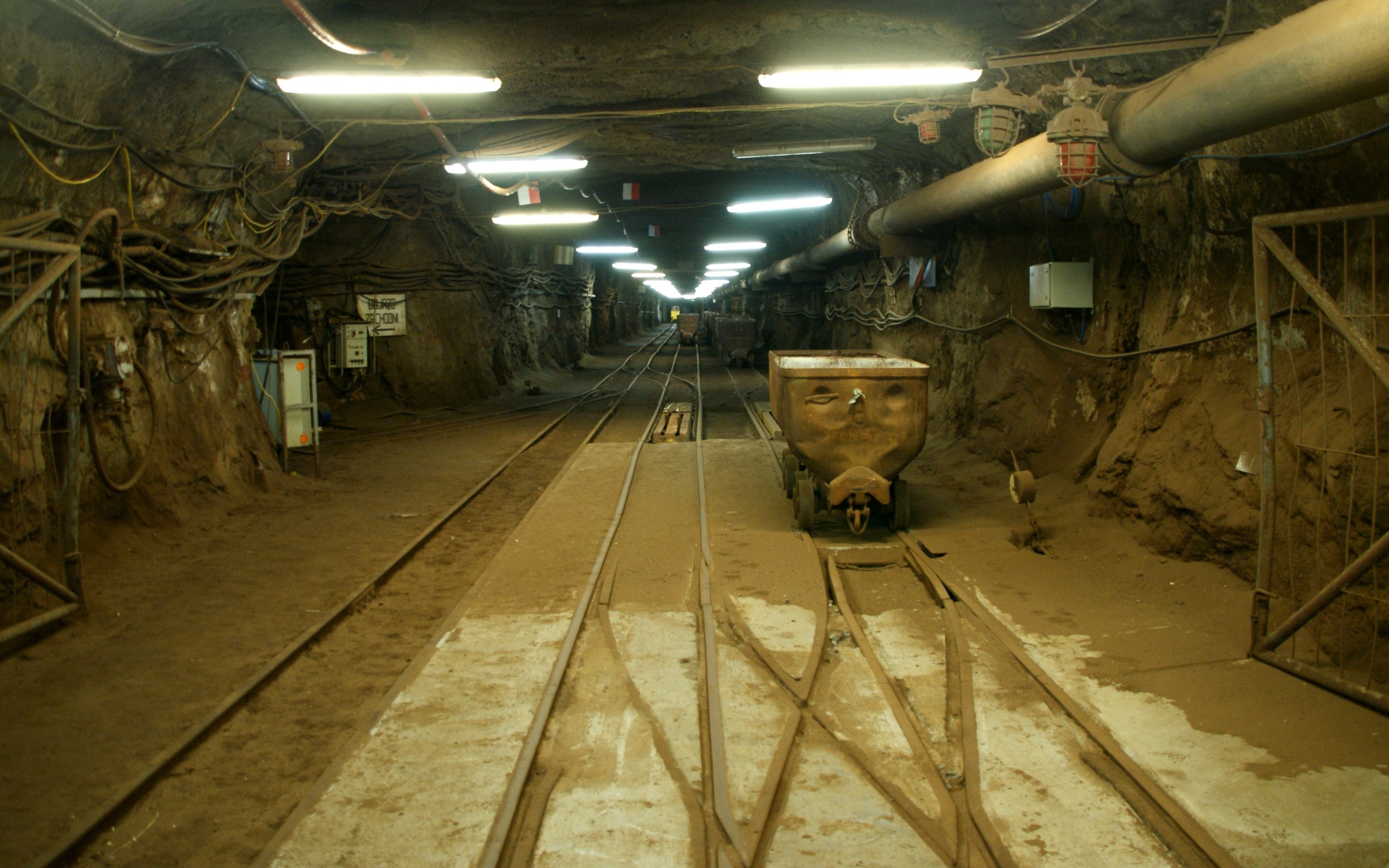 Underground mine tunnel with train tracks and carts in Poland HD Wallpaper