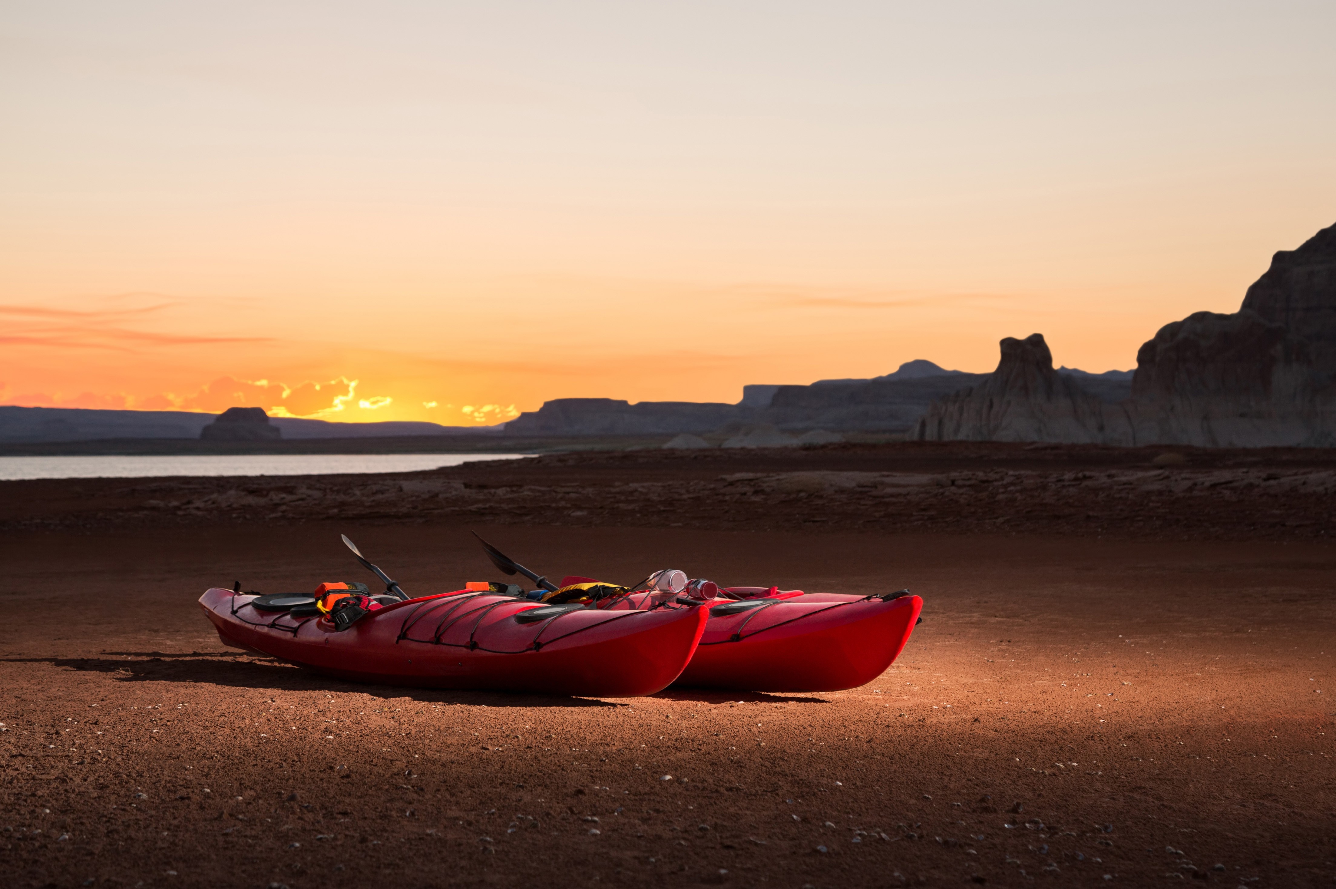Two red kayaks on a sandy shore at sunset HD Wallpaper