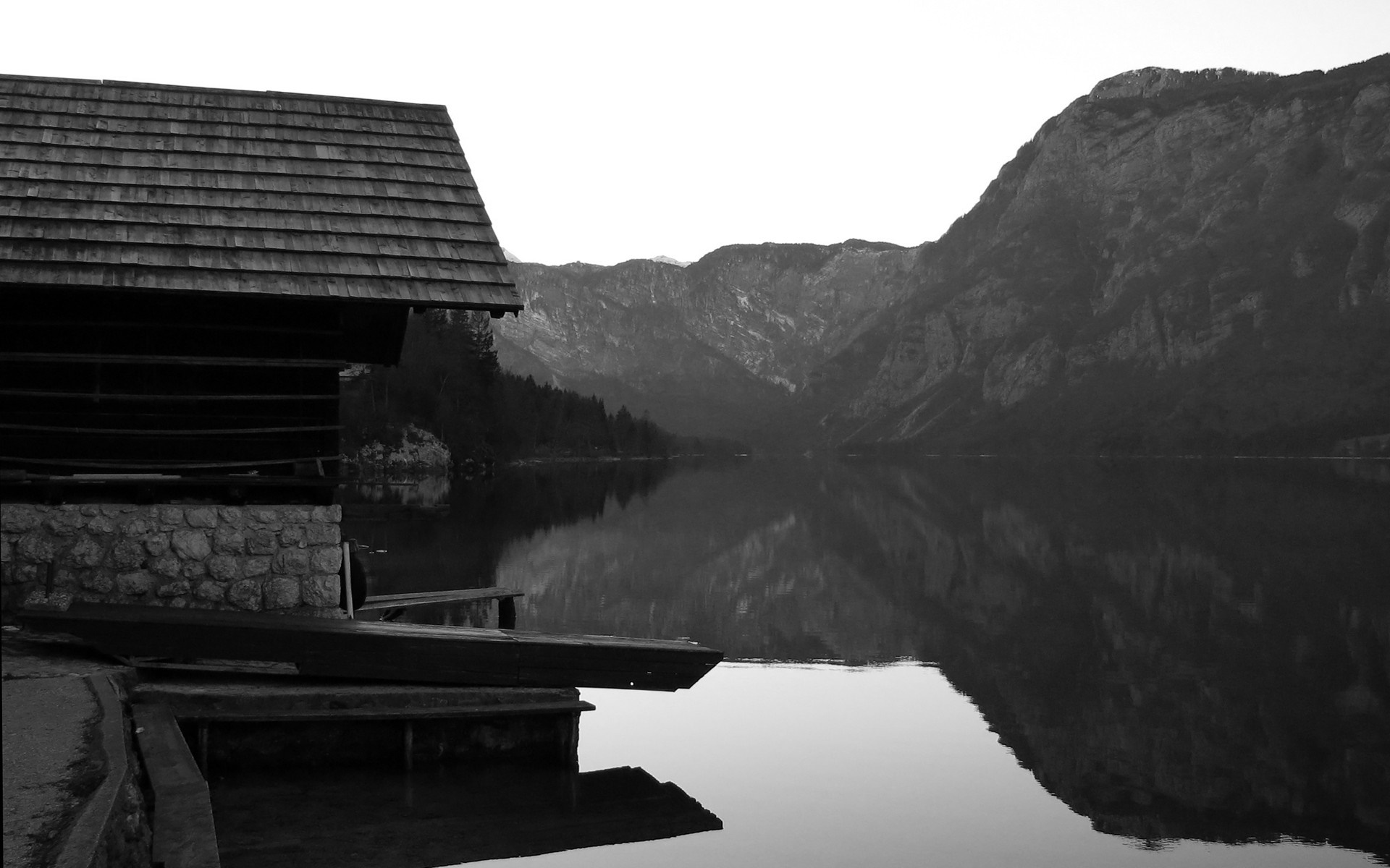 Boathouse on a calm lake with mountains reflected HD Wallpaper