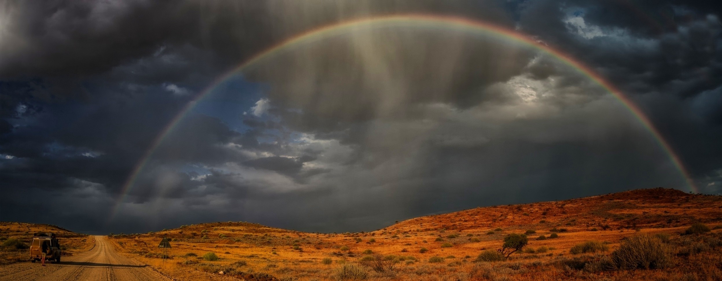 Rainbow over a dirt road in Namibia HD Wallpaper
