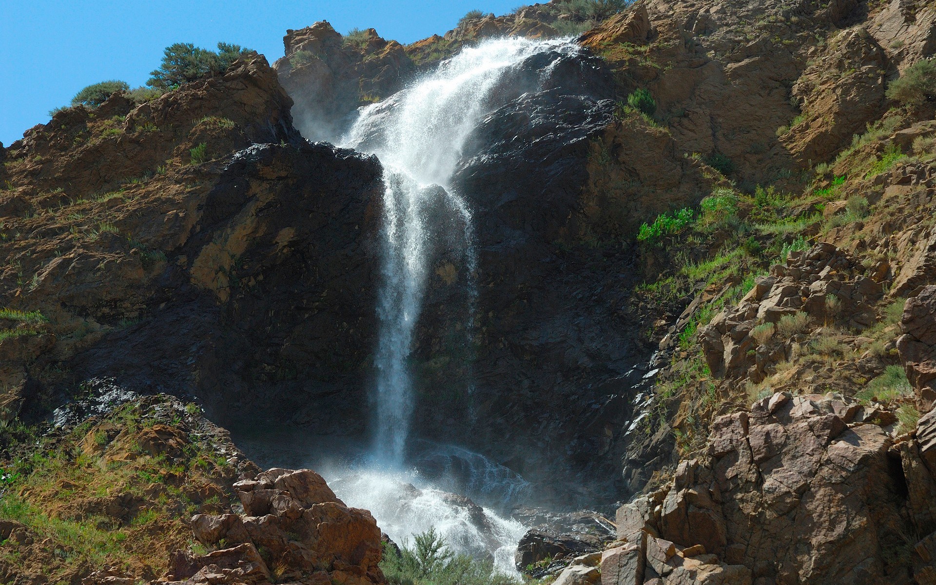 Waterfall cascading down a rocky mountainside HD Wallpaper