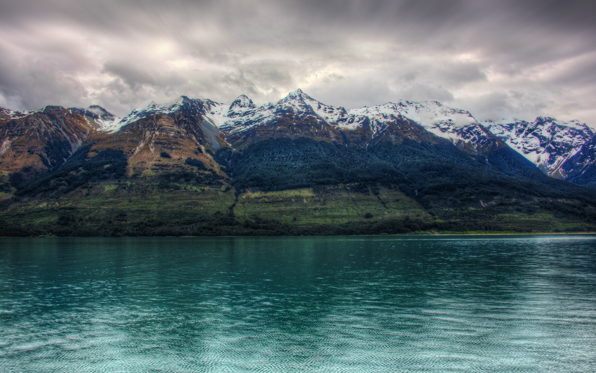 Snow-capped mountains over a turquoise lake HD Wallpaper