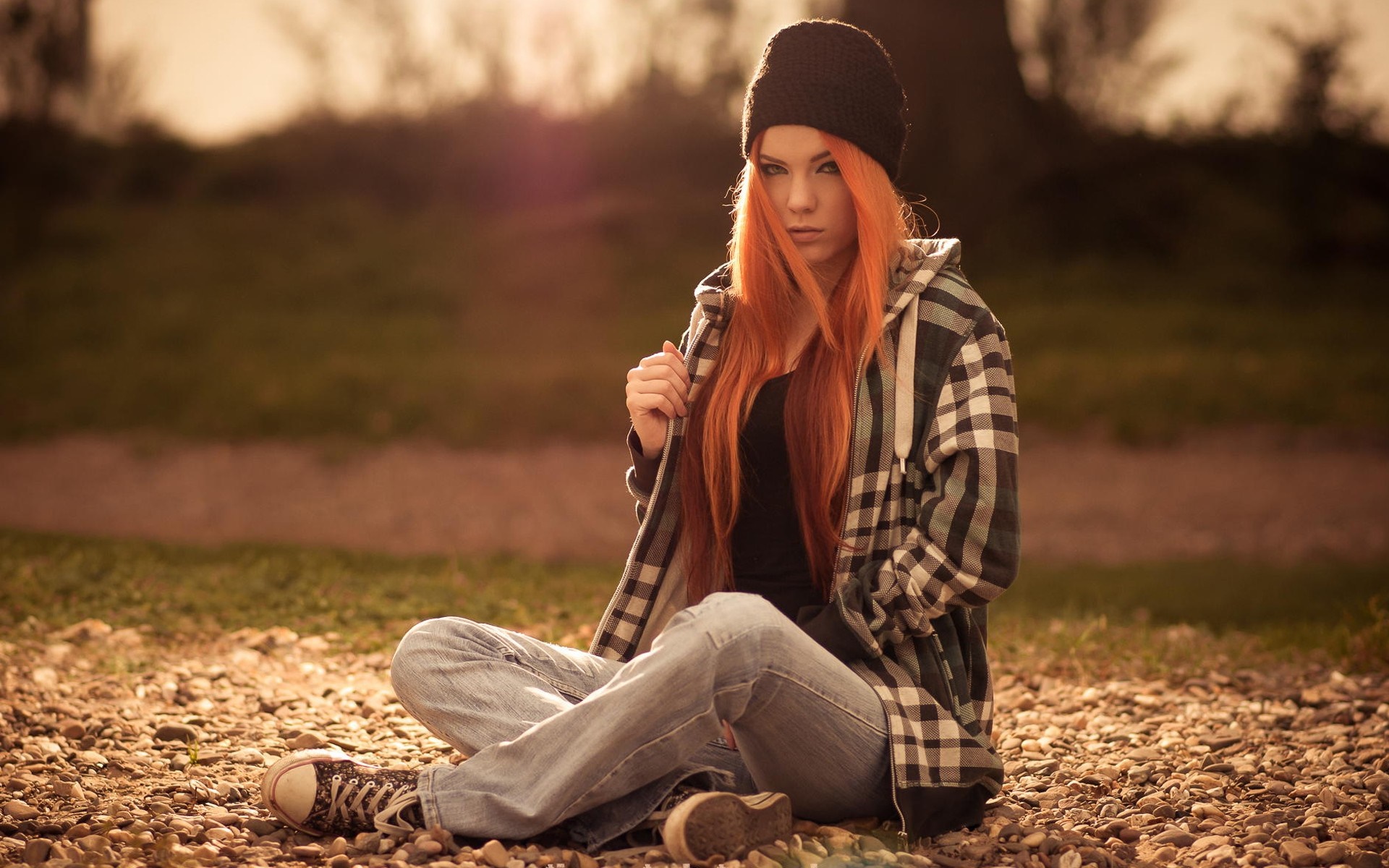 Redhead woman in beanie and plaid jacket sitting outdoors HD Wallpaper