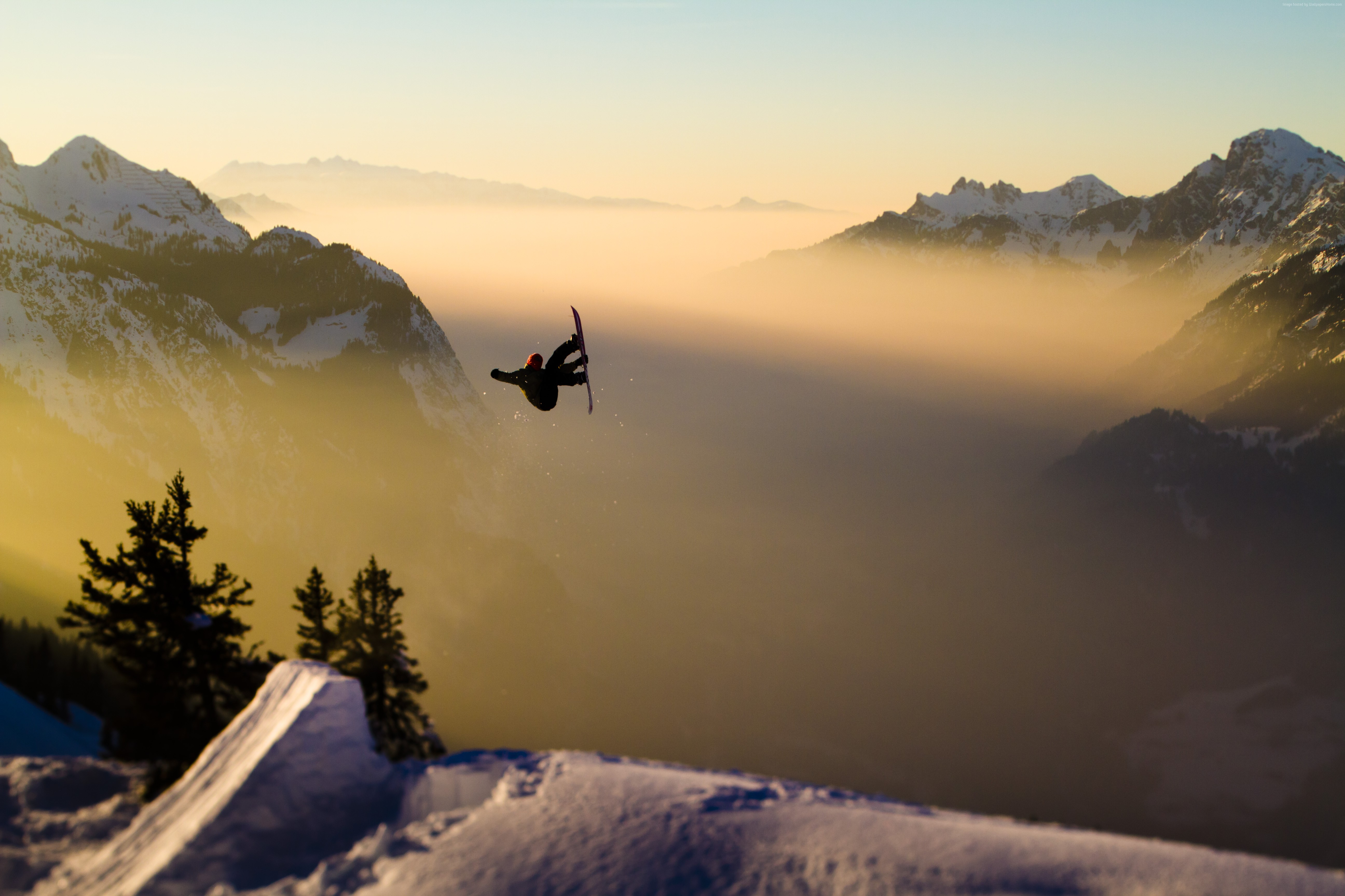 Snowboarder jumping over a foggy mountain valley at sunset HD Wallpaper