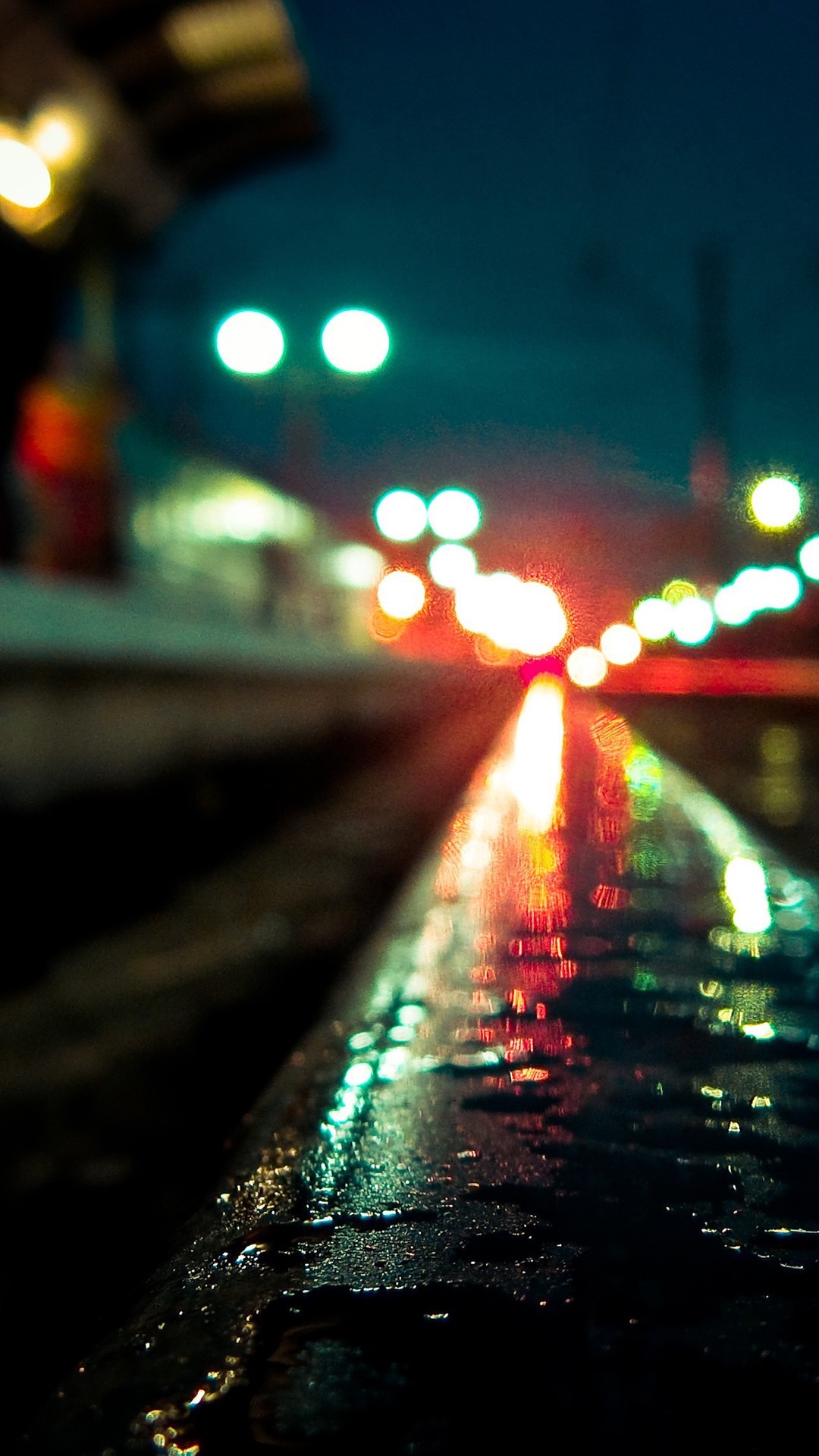 Bokeh lights reflecting on wet train tracks at night HD Wallpaper