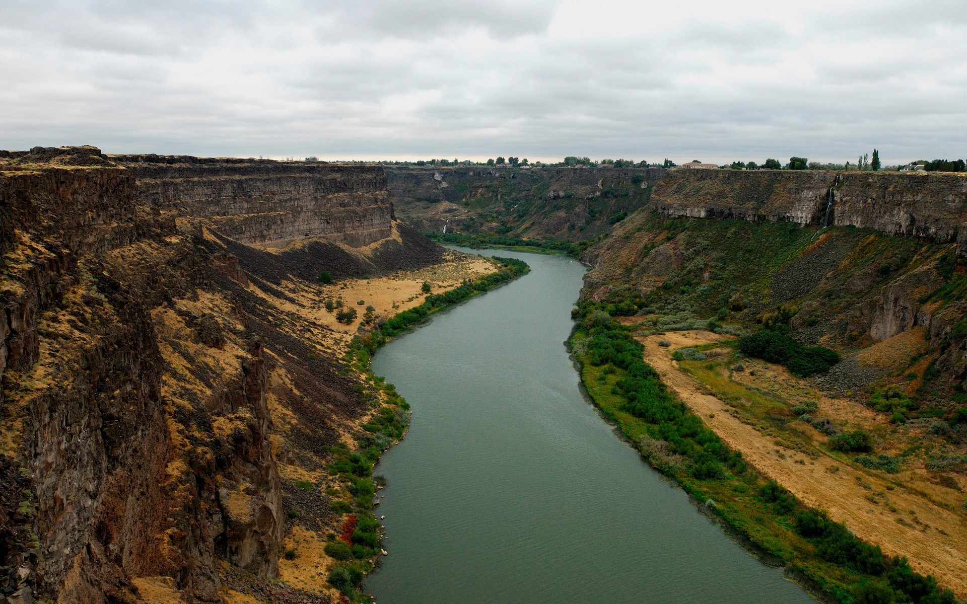 River flowing through a canyon under a cloudy sky HD Wallpaper
