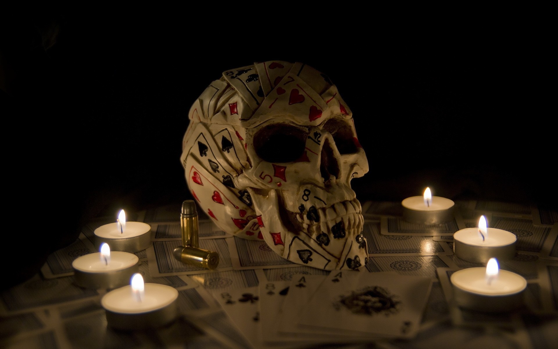 Skull decorated with playing cards and candles HD Wallpaper