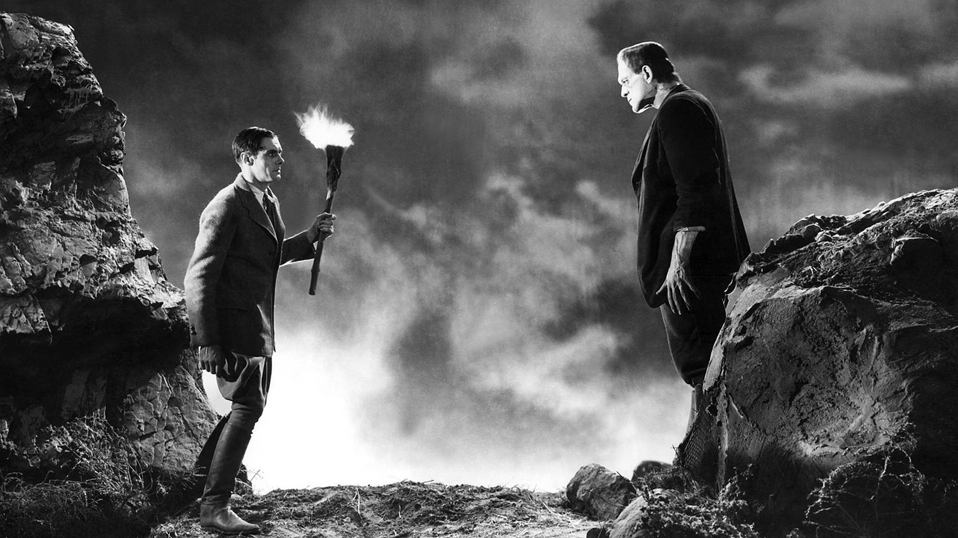 Monster of Frankenstein and man with torch on rocks HD Wallpaper