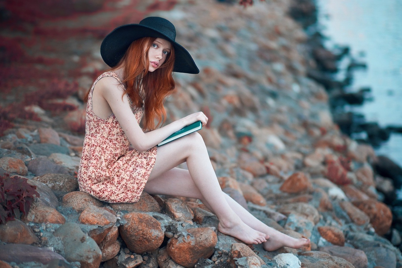 Redhead Woman in Floral Dress Sitting on Rocks by Water HD Wallpaper