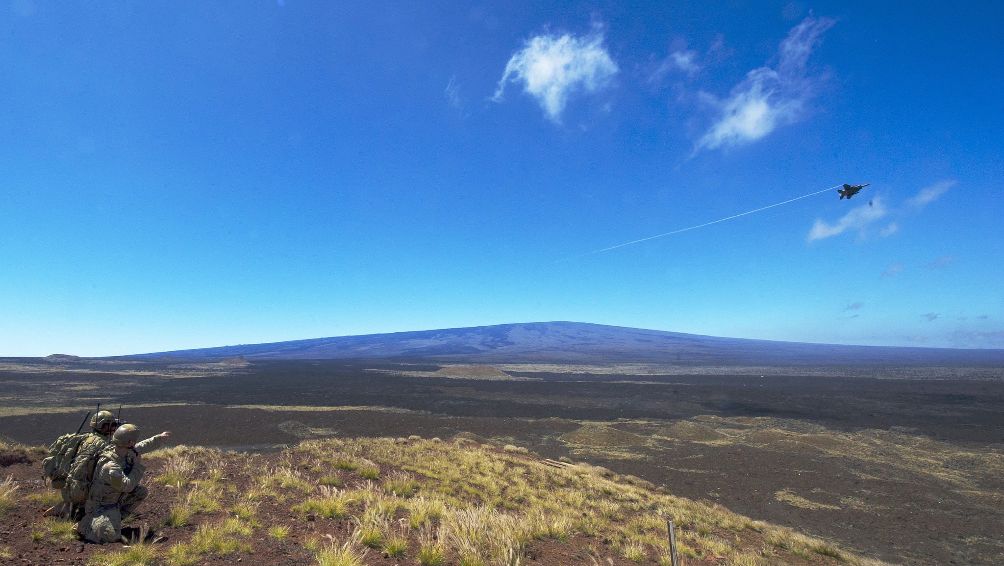 Military aircraft flying over a volcanic landscape with soldiers HD Wallpaper