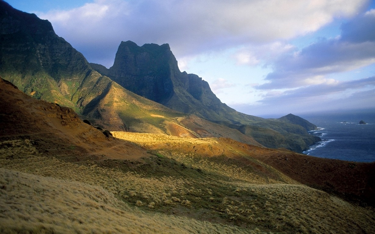 Mountainous coastal landscape with dramatic peaks and ocean HD Wallpaper
