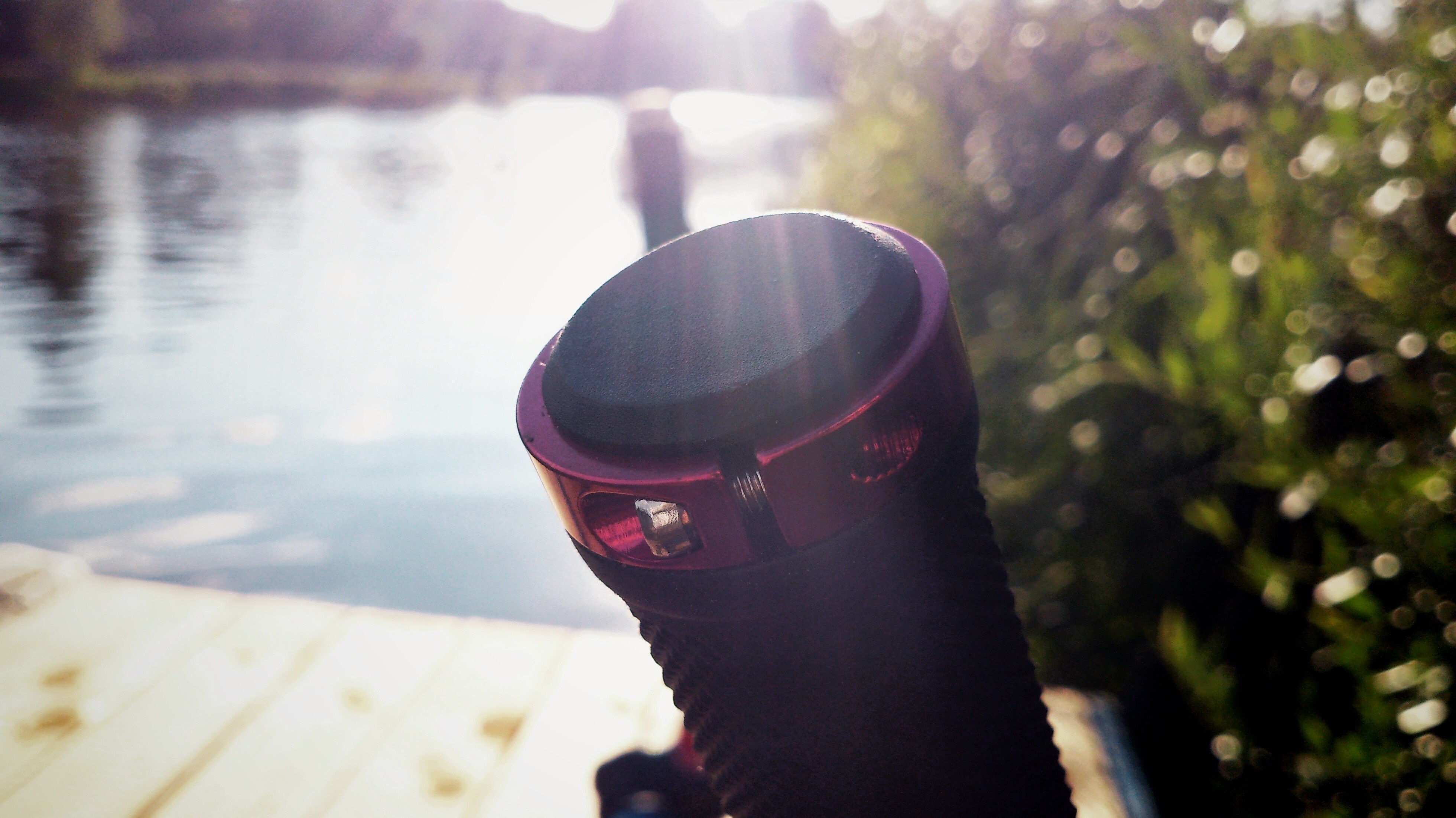 Close-up of a bicycle handlebar grip by a lake at sunset HD Wallpaper