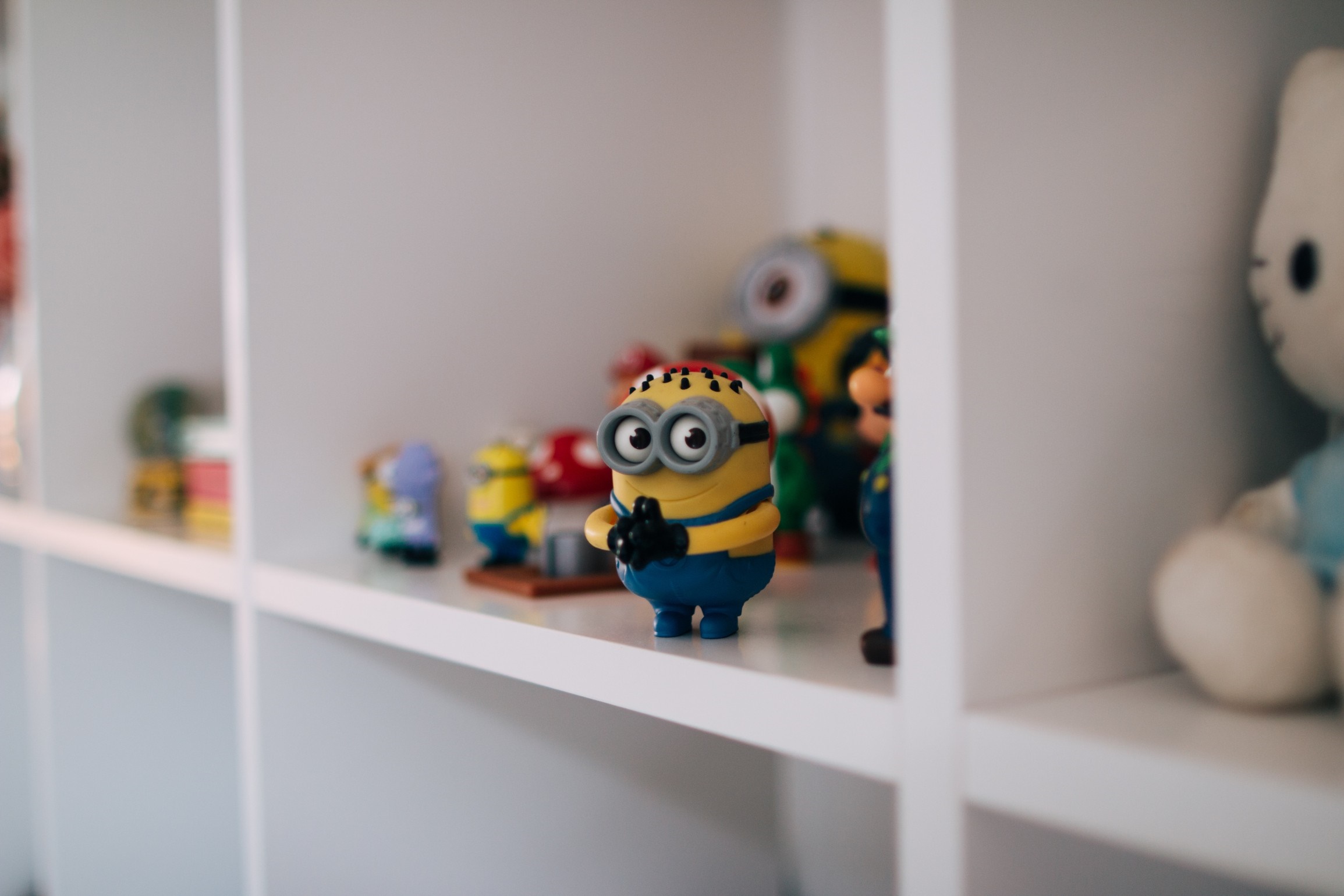Minion toys on a shelf with other toys HD Wallpaper