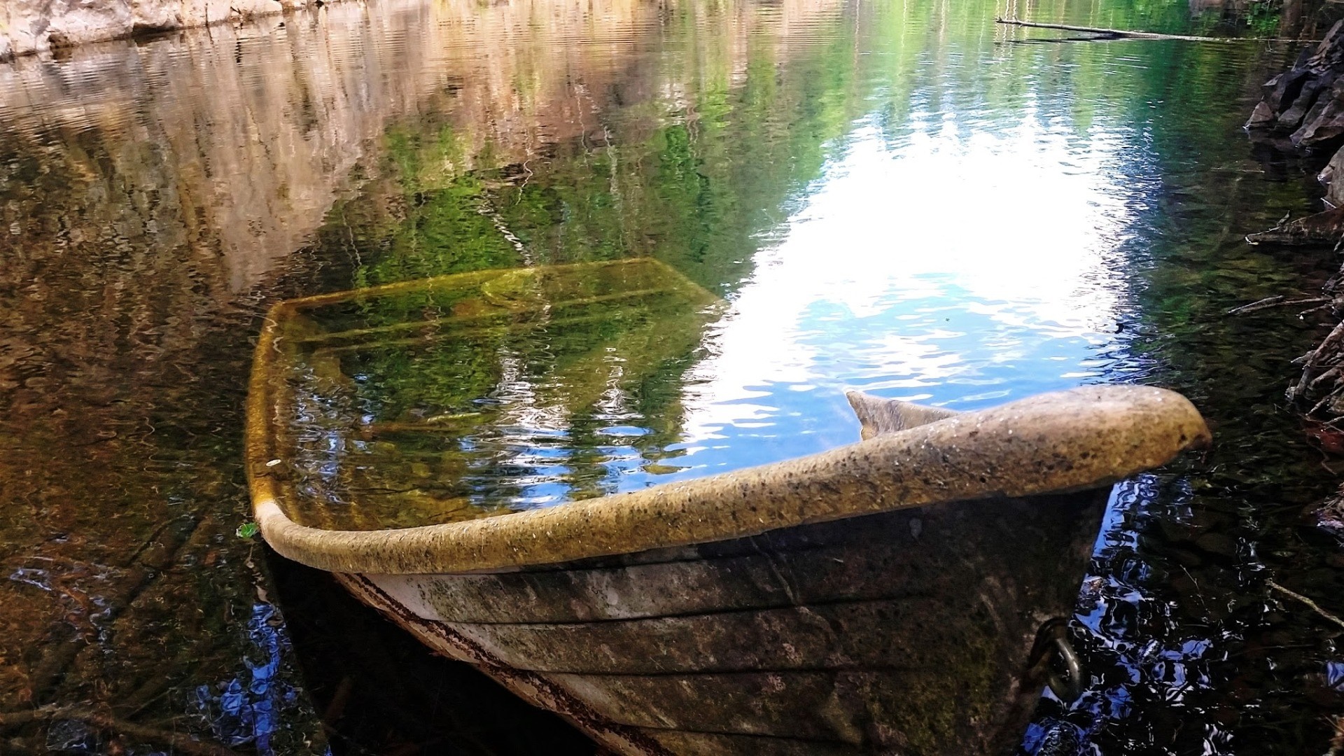 Abandoned boat submerged in a calm body of water with reflections HD Wallpaper