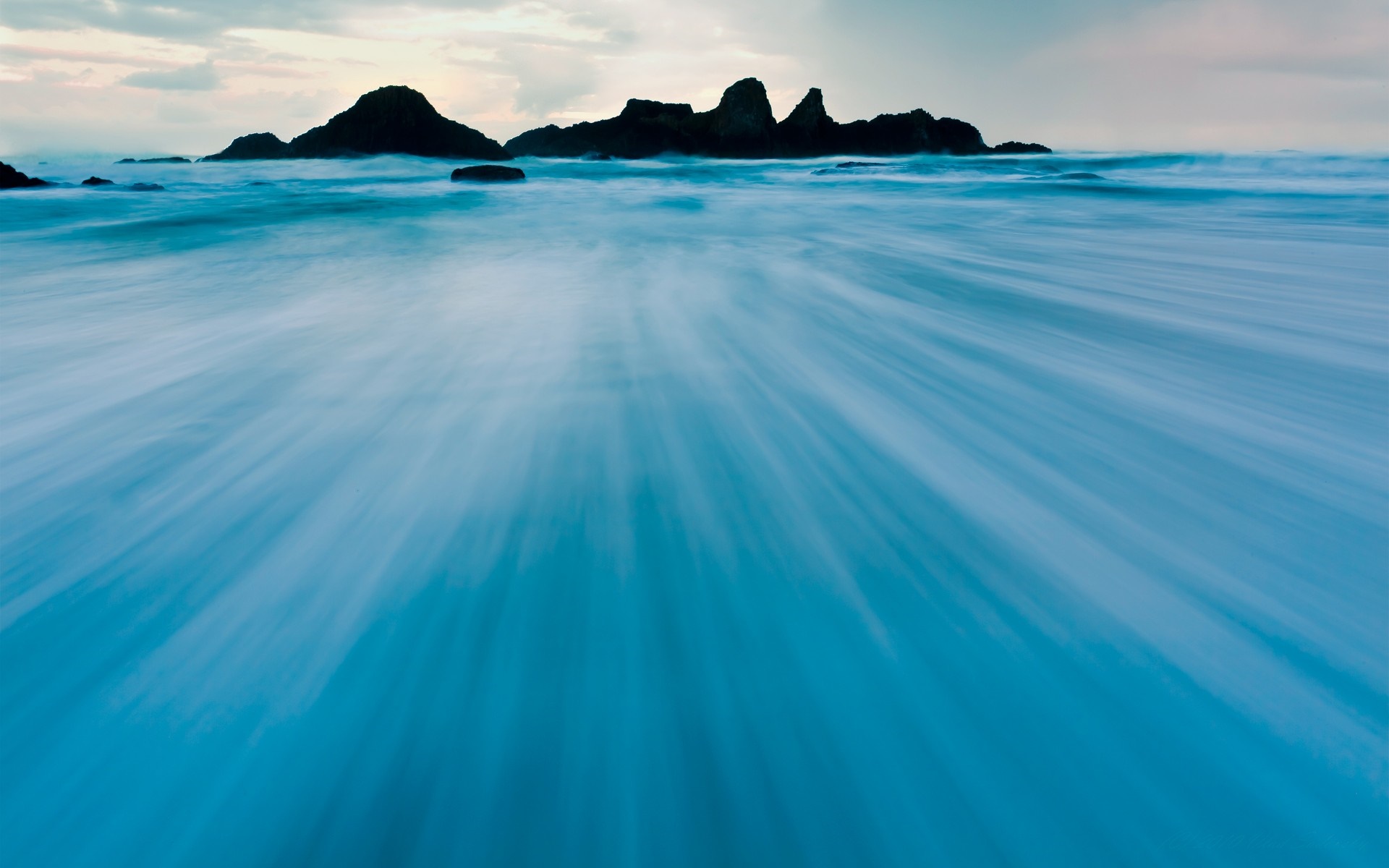 Long exposure of ocean waves crashing on rocky shore HD Wallpaper