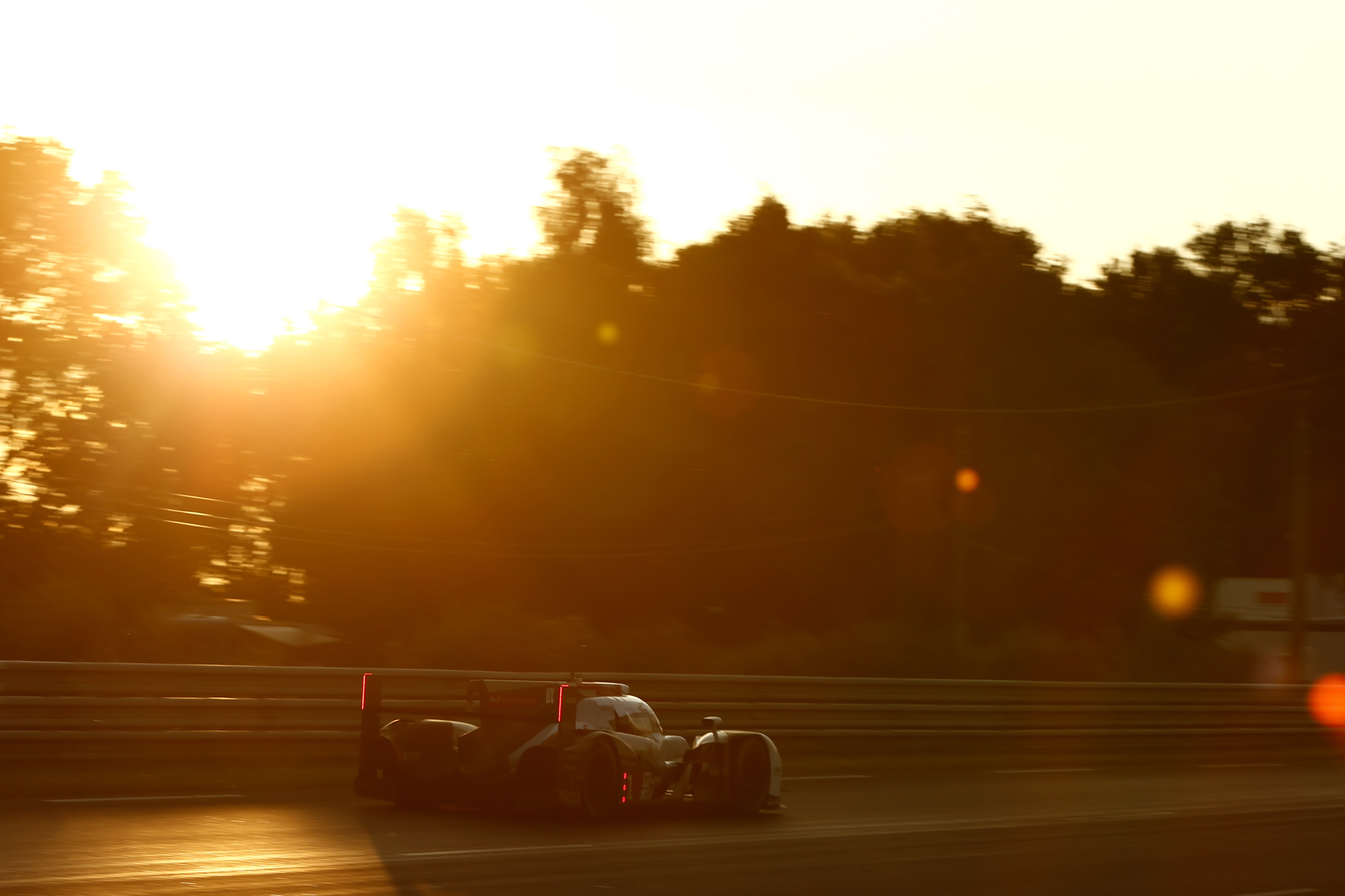 Race car speeding on a track at sunset HD Wallpaper