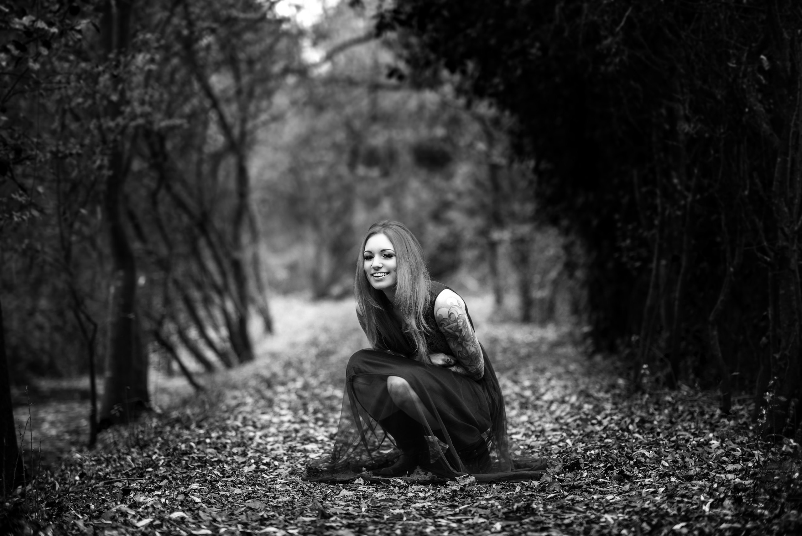 Woman with tattoos squatting in a forest HD Wallpaper