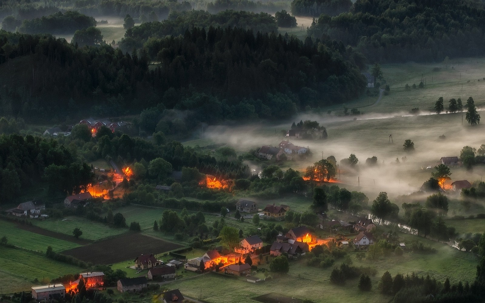 Aerial view of misty villages with glowing lights at dawn HD Wallpaper
