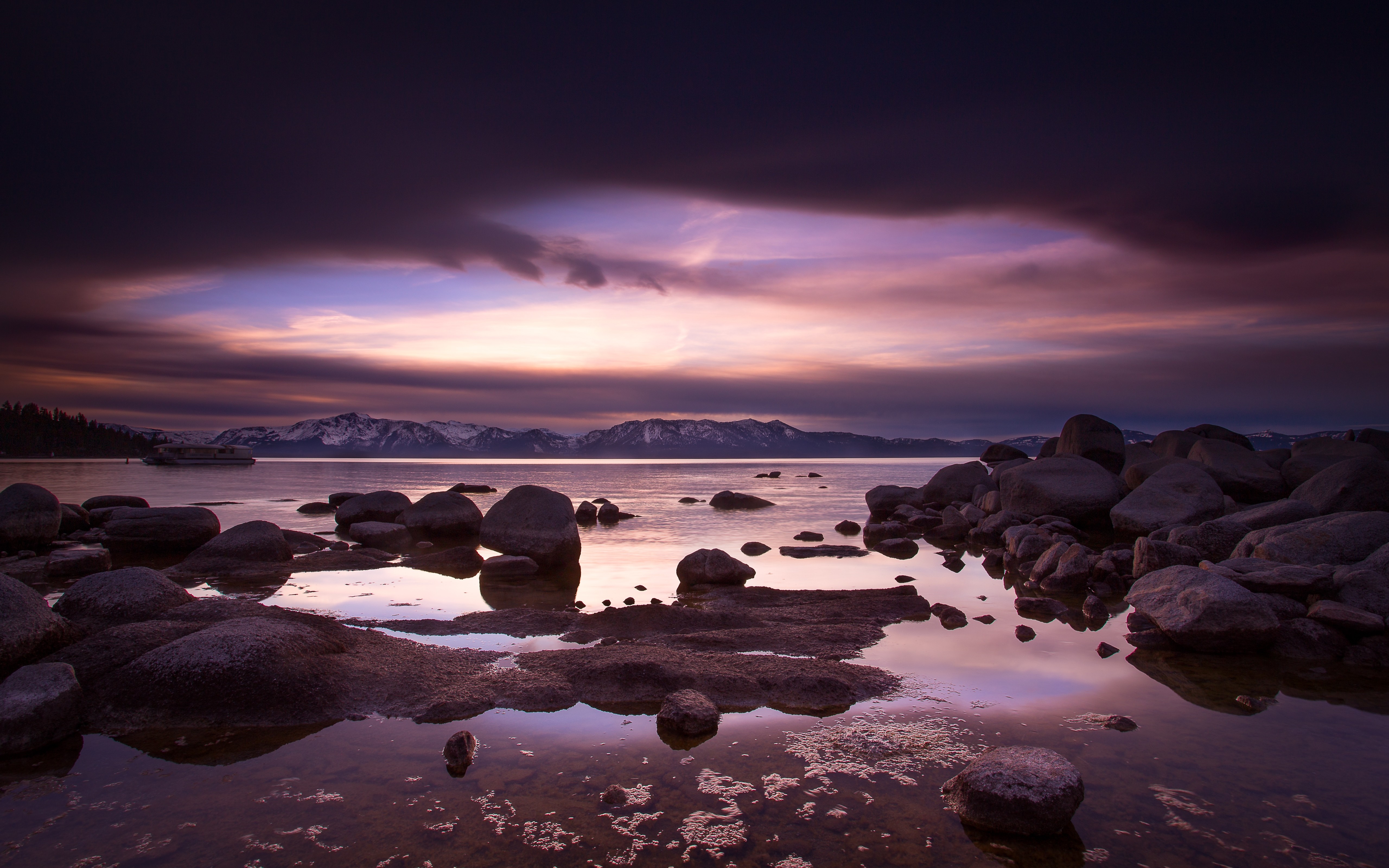Sunset over a rocky shore with mountains in the distance HD Wallpaper