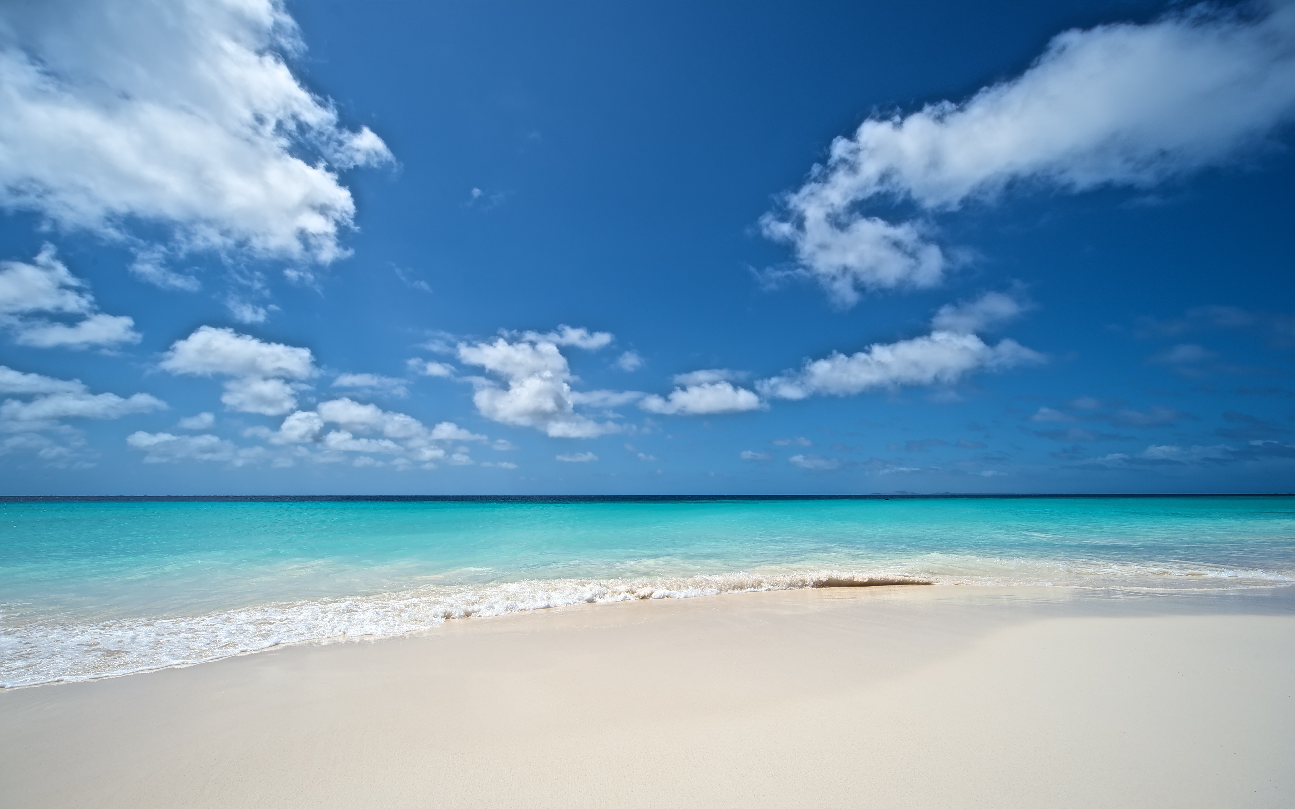 Turquoise ocean waves on a white sand beach under a blue sky HD Wallpaper