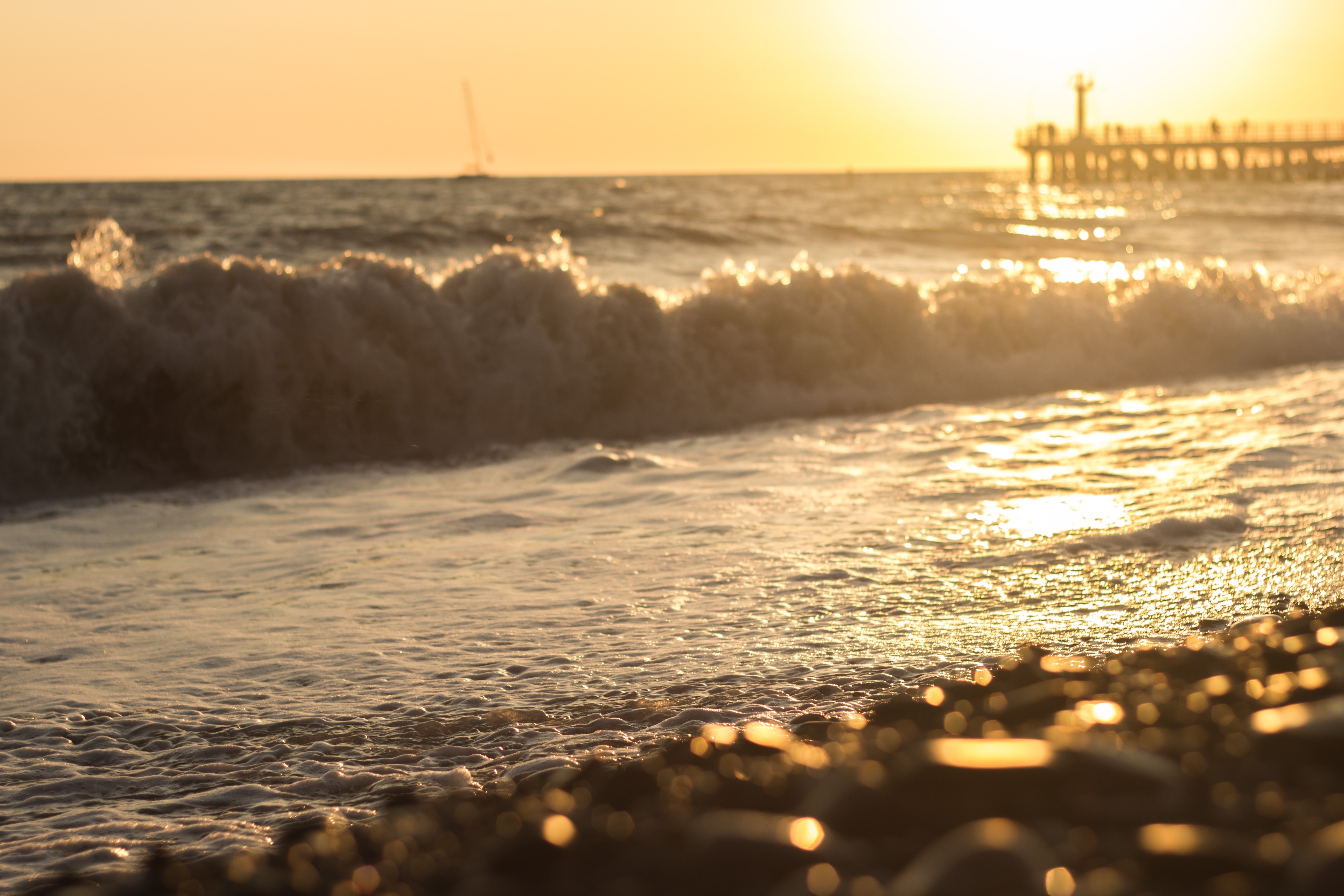 Sunset over the ocean with waves and a pier HD Wallpaper