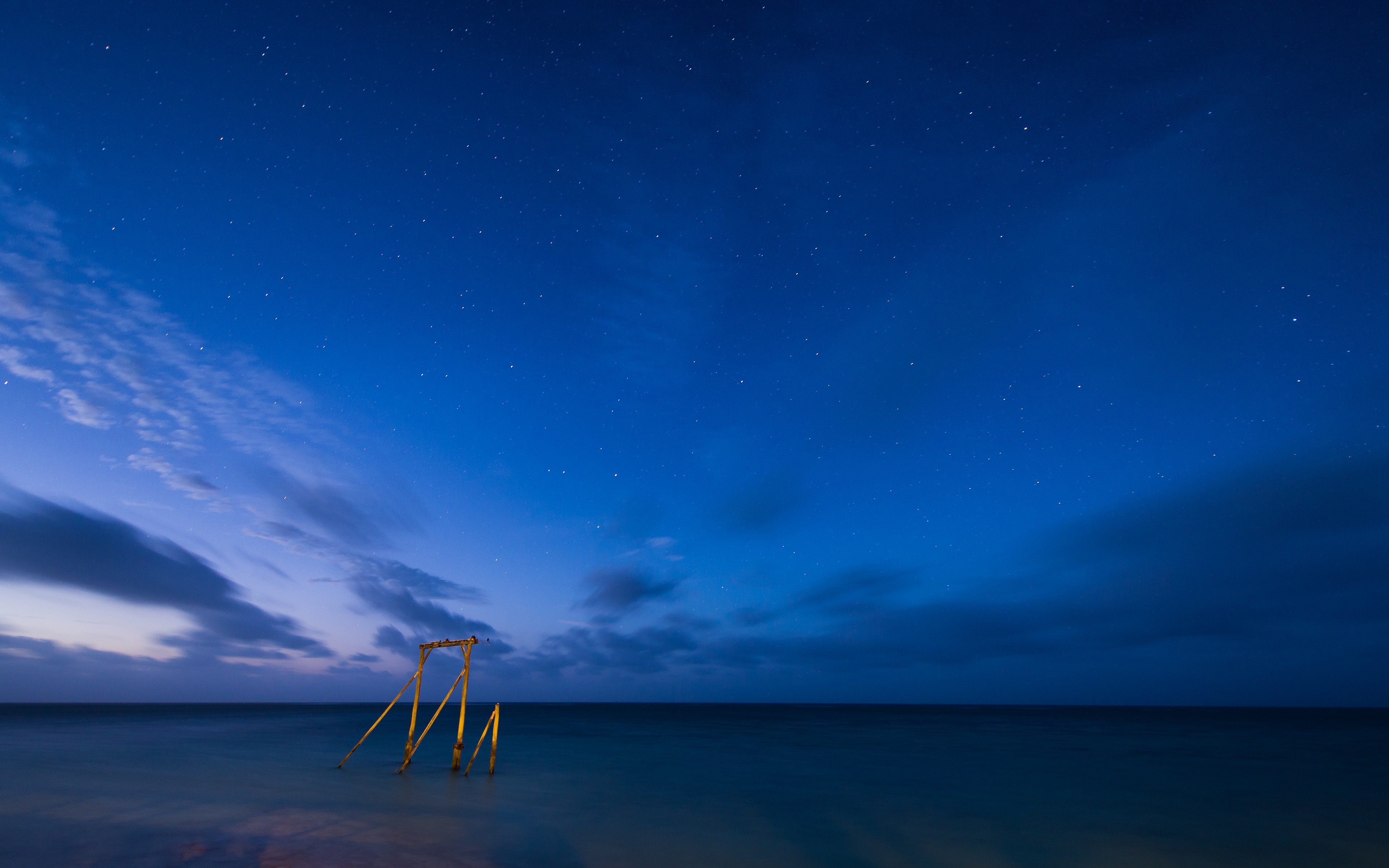Wooden structure in the sea under a starry night sky HD Wallpaper