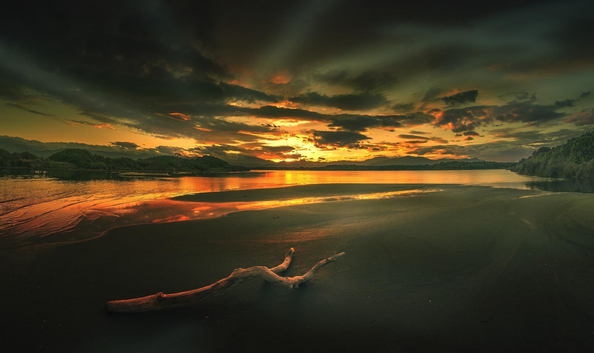 Sunset over a calm body of water with a driftwood log on the beach HD Wallpaper