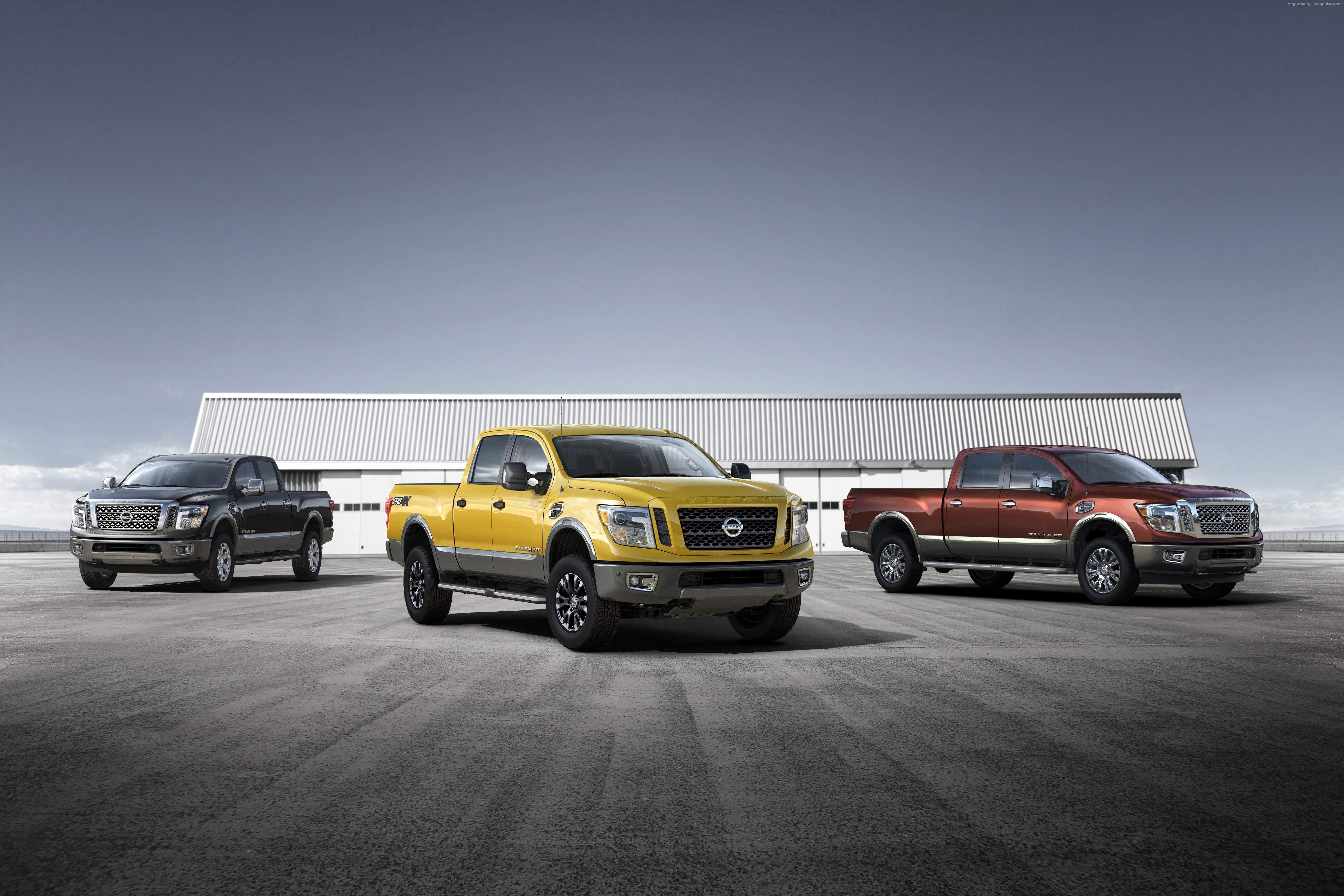 Three Nissan Titan trucks parked in front of a building HD Wallpaper