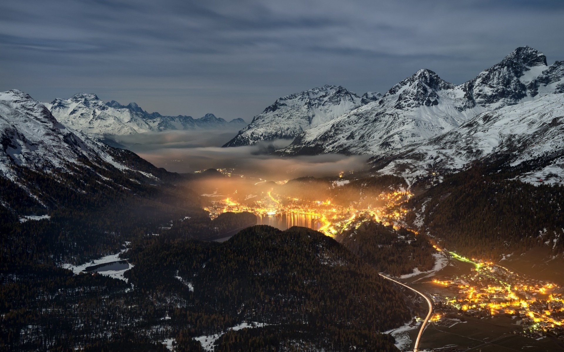 Valley town lights at night with snowy mountains HD Wallpaper