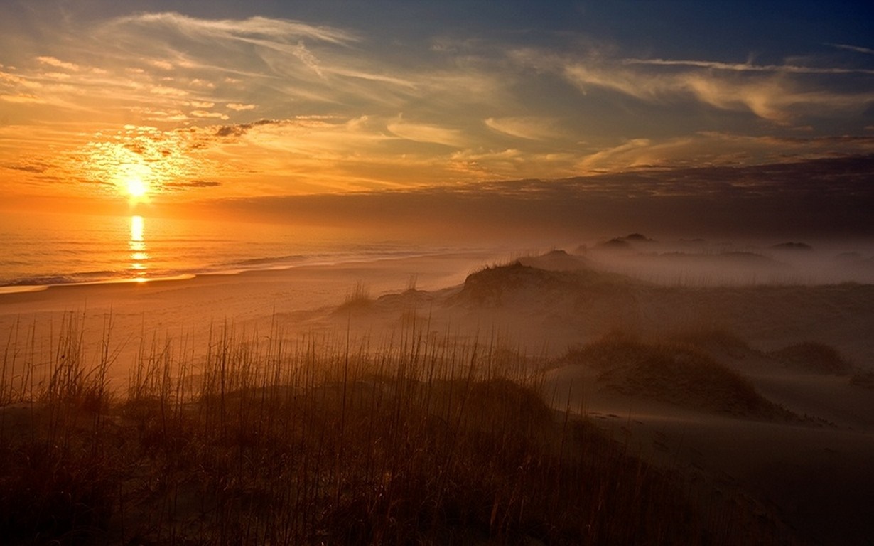 Sunset over a misty beach with sand dunes and ocean waves HD Wallpaper