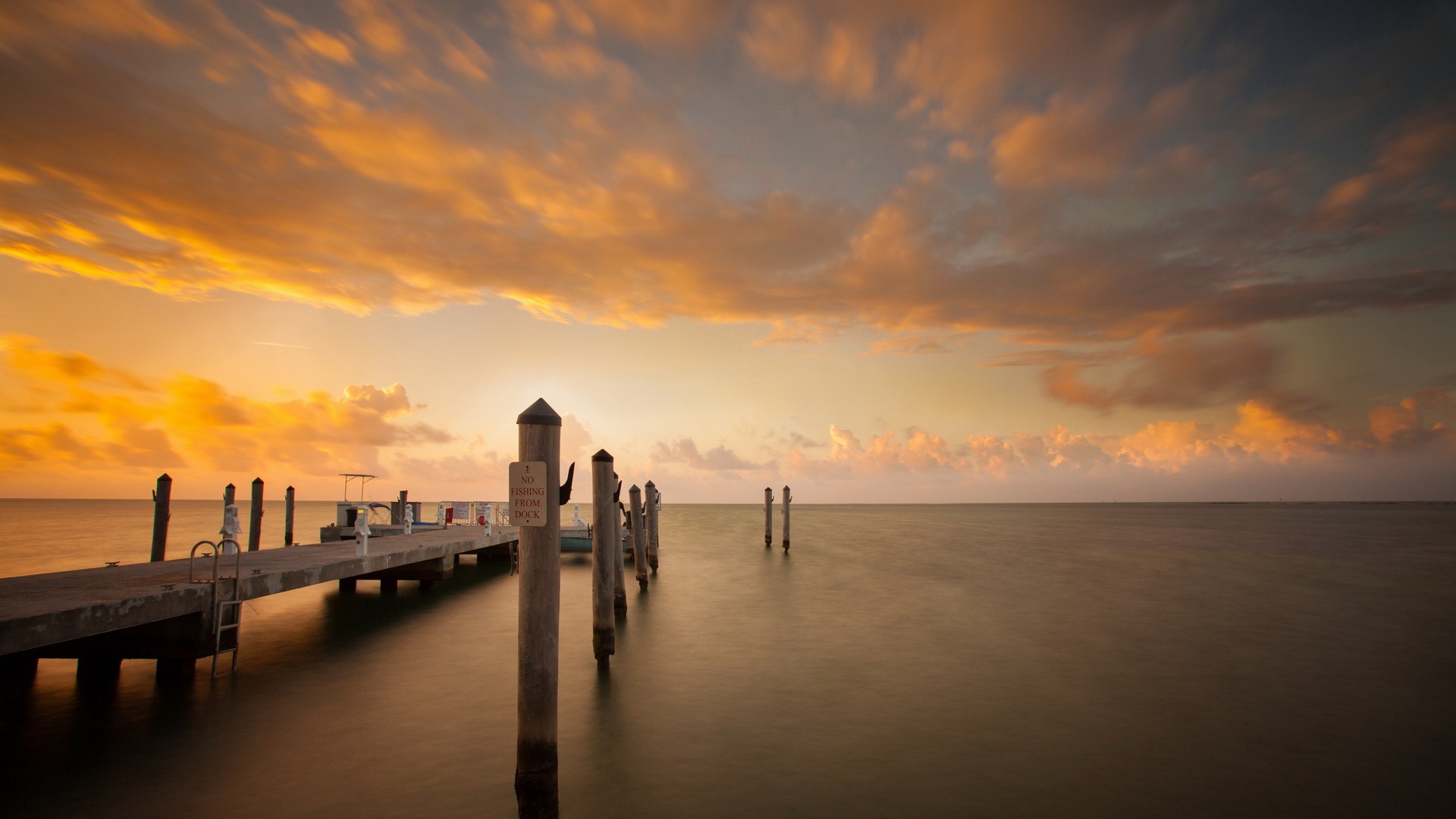 Dock with posts at sunset over the ocean HD Wallpaper